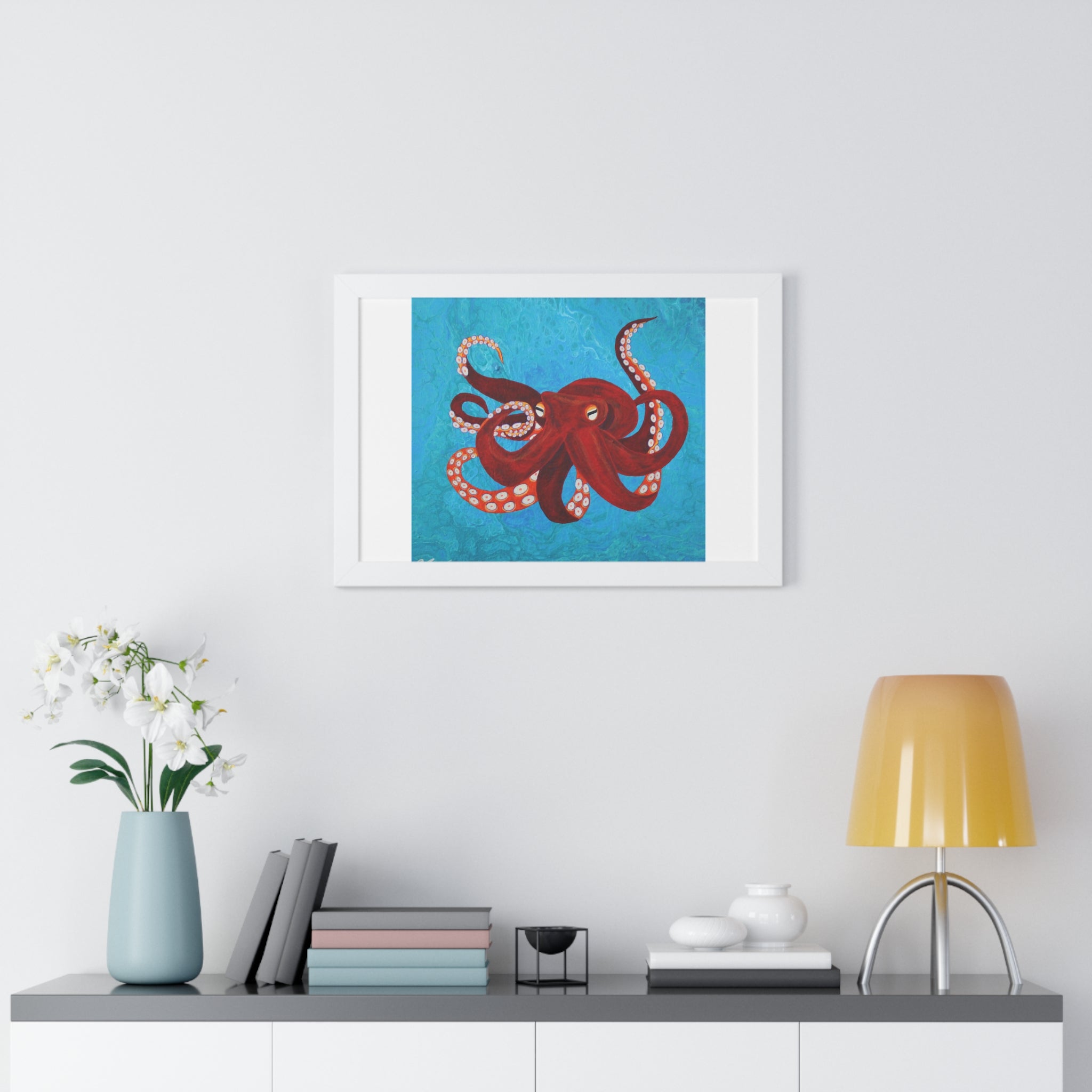 Framed artwork of a red octopus on a blue background above a shelf with decor items.