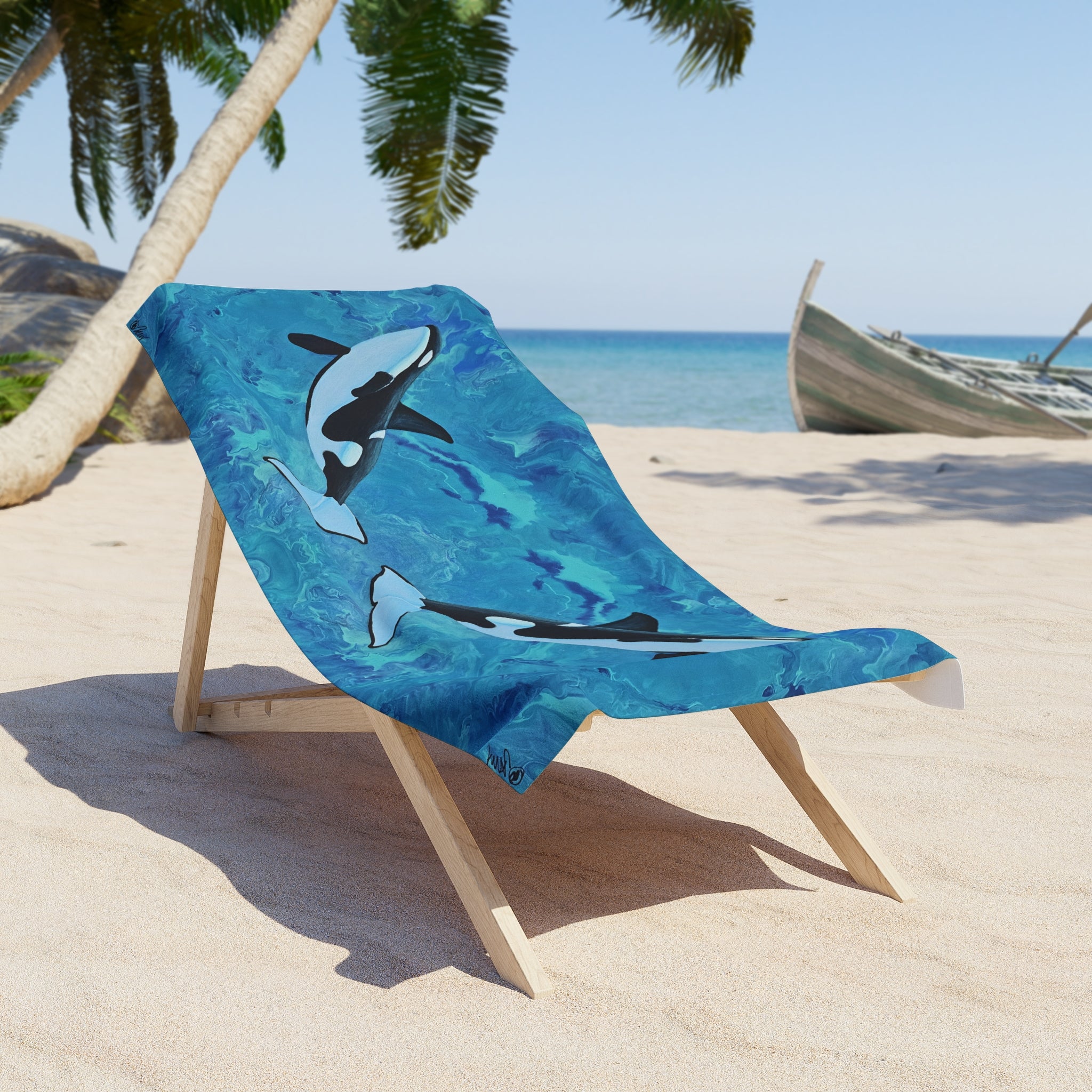 Beach towel/blanket with shark design draped over a wooden chair on a sandy beach.