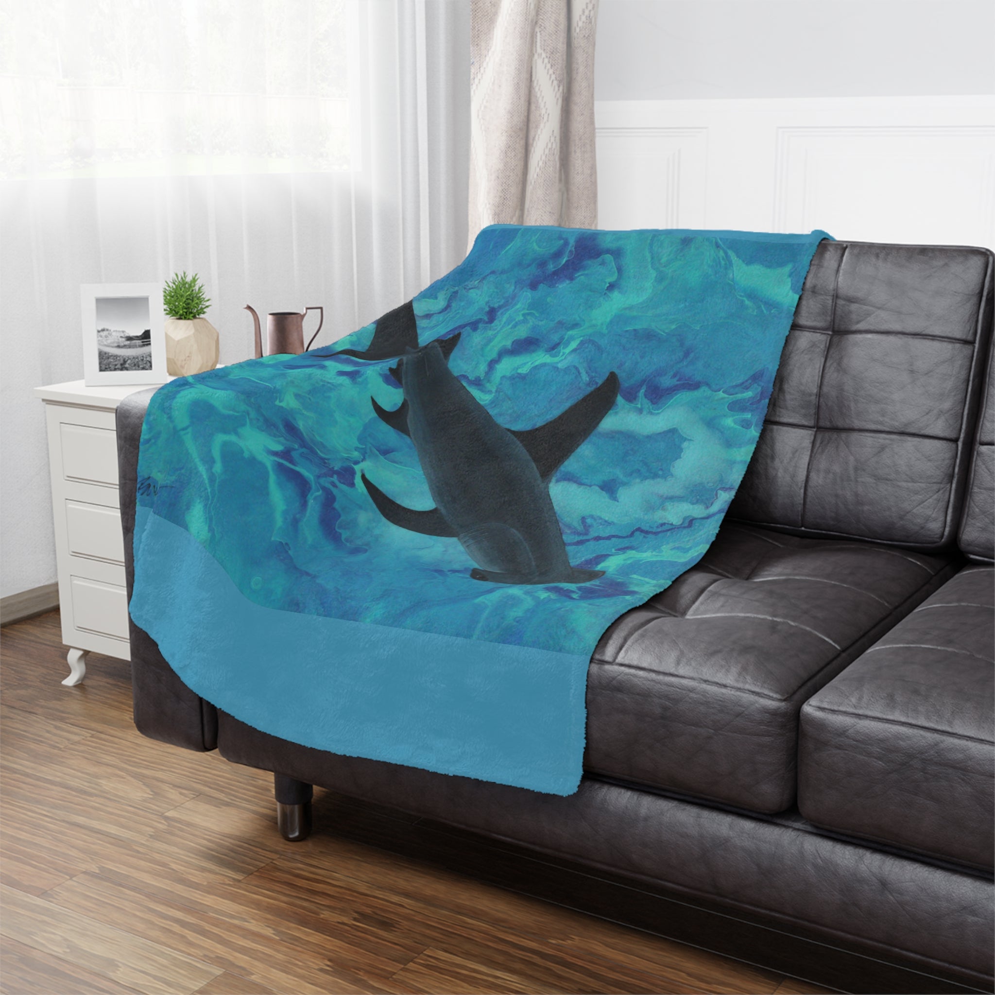 Blanket with shark design draped over a gray sofa in a living room.