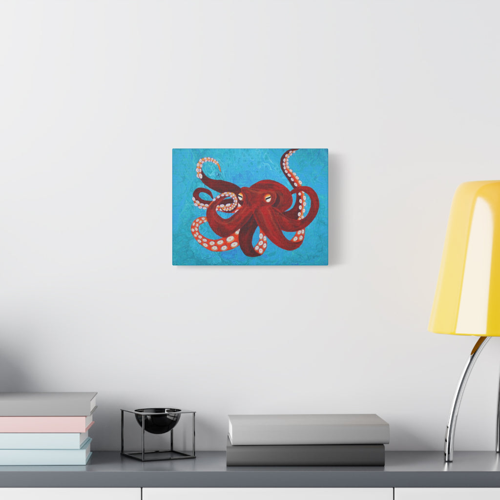 Red octopus painting on a wall above a desk with books and a lamp.