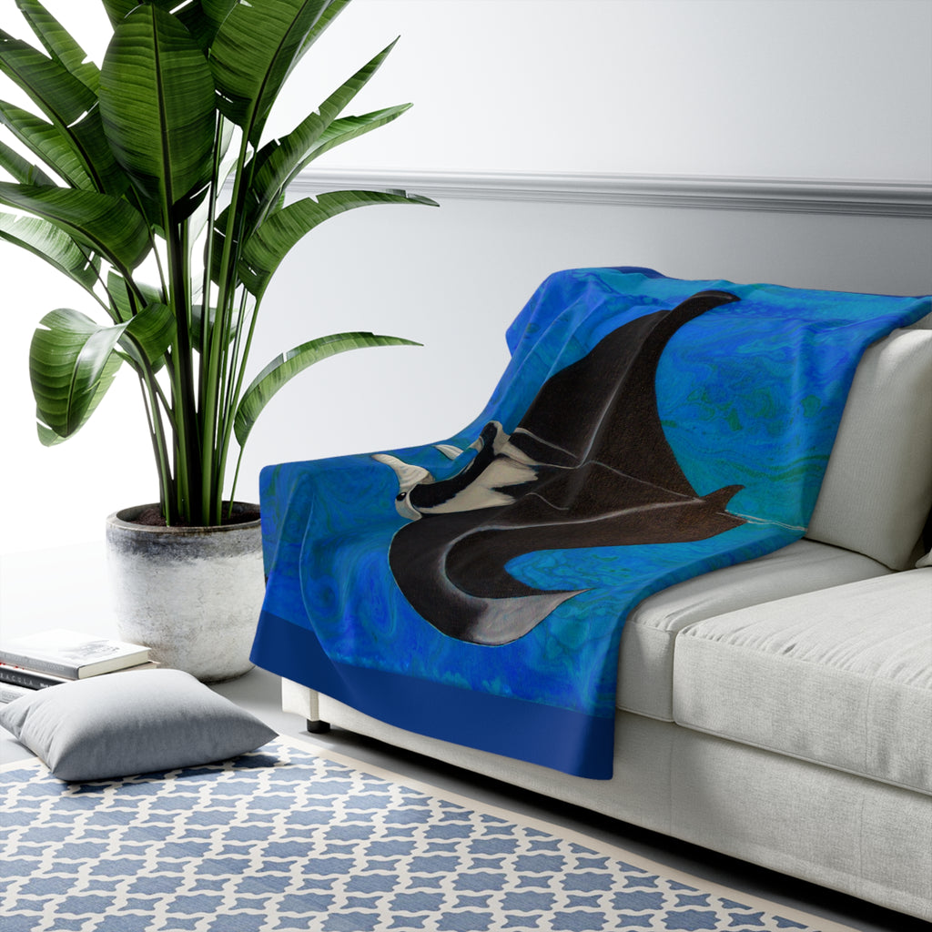 Blue blanket with a manta ray design on a white couch in a living room.