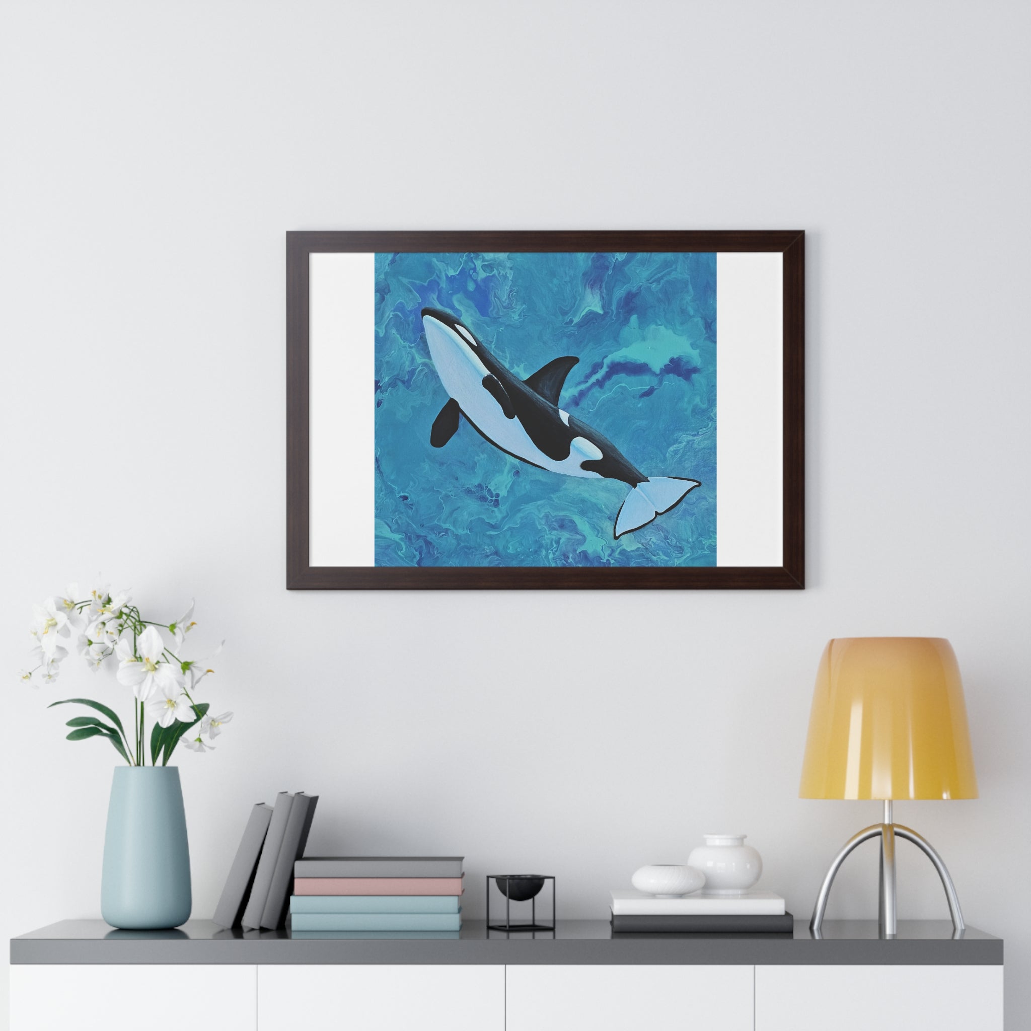 Framed artwork of a whale on a wall above a shelf with decor items.