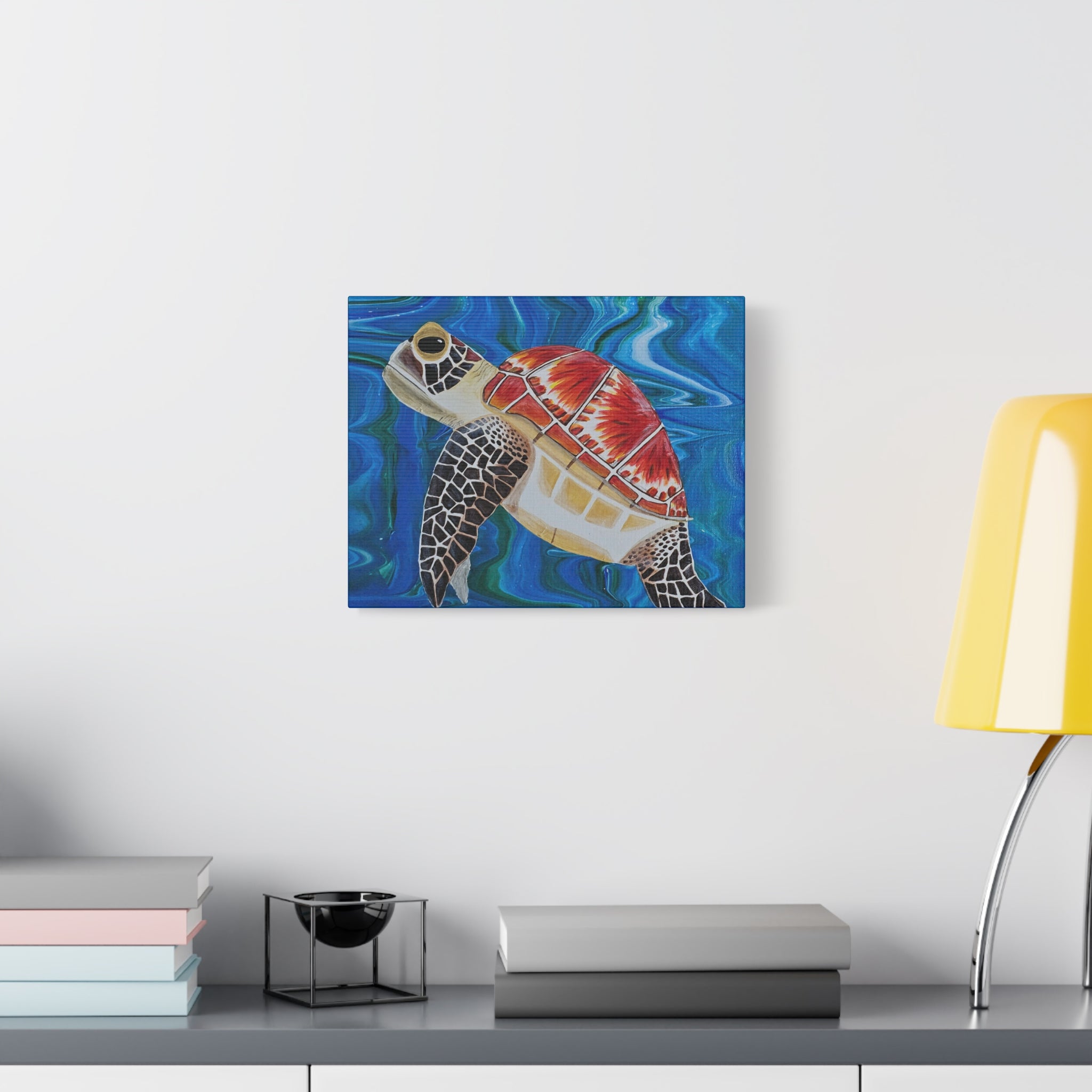 Canvas print of a colorful turtle on a wall above a desk with books and a lamp.