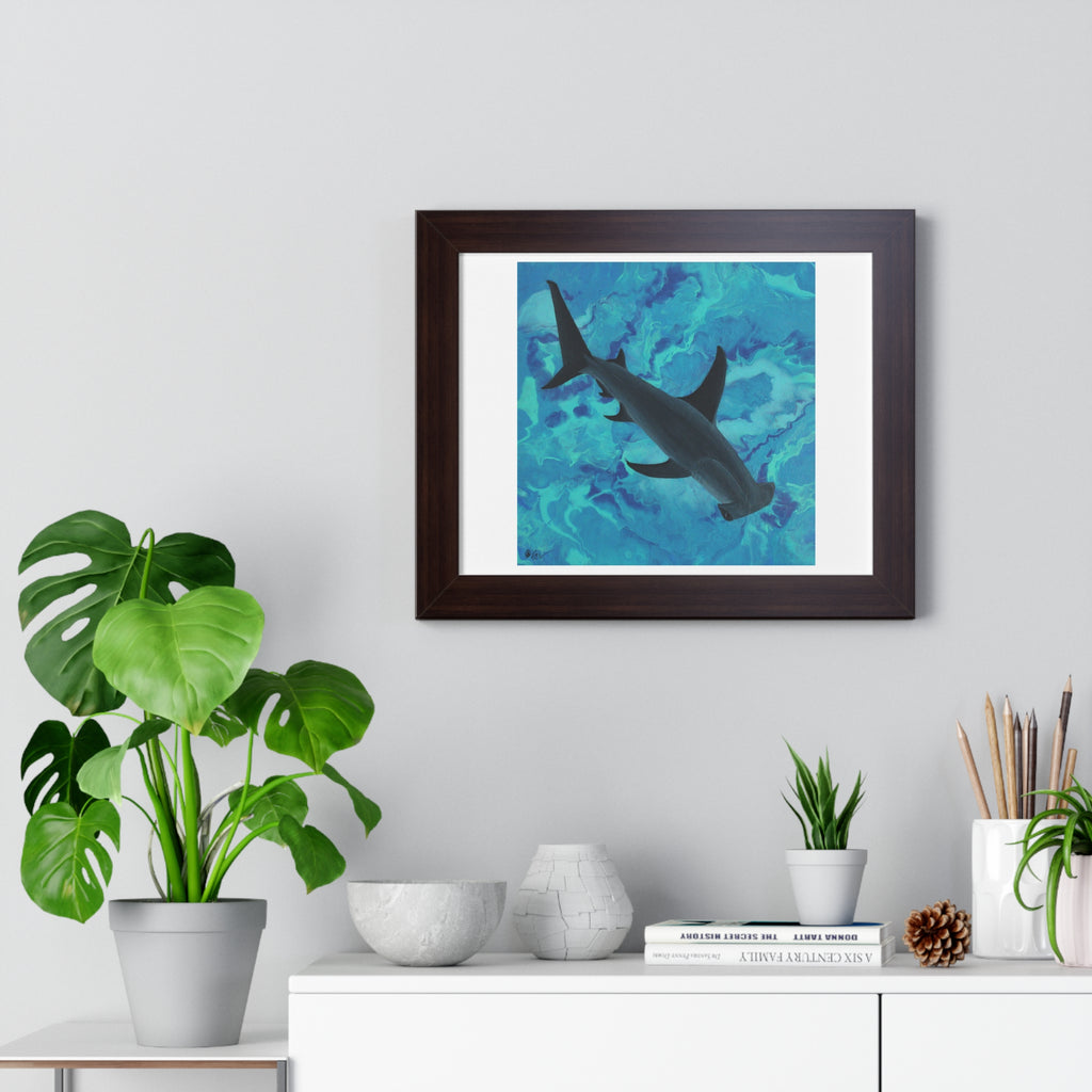 Framed artwork of a shark in an underwater scene on a wall above a desk with plants and decor.
