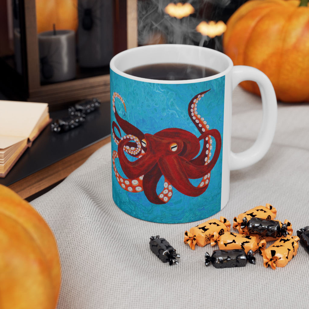 Mug with a red octopus design on a table with Halloween-themed treats and pumpkins.