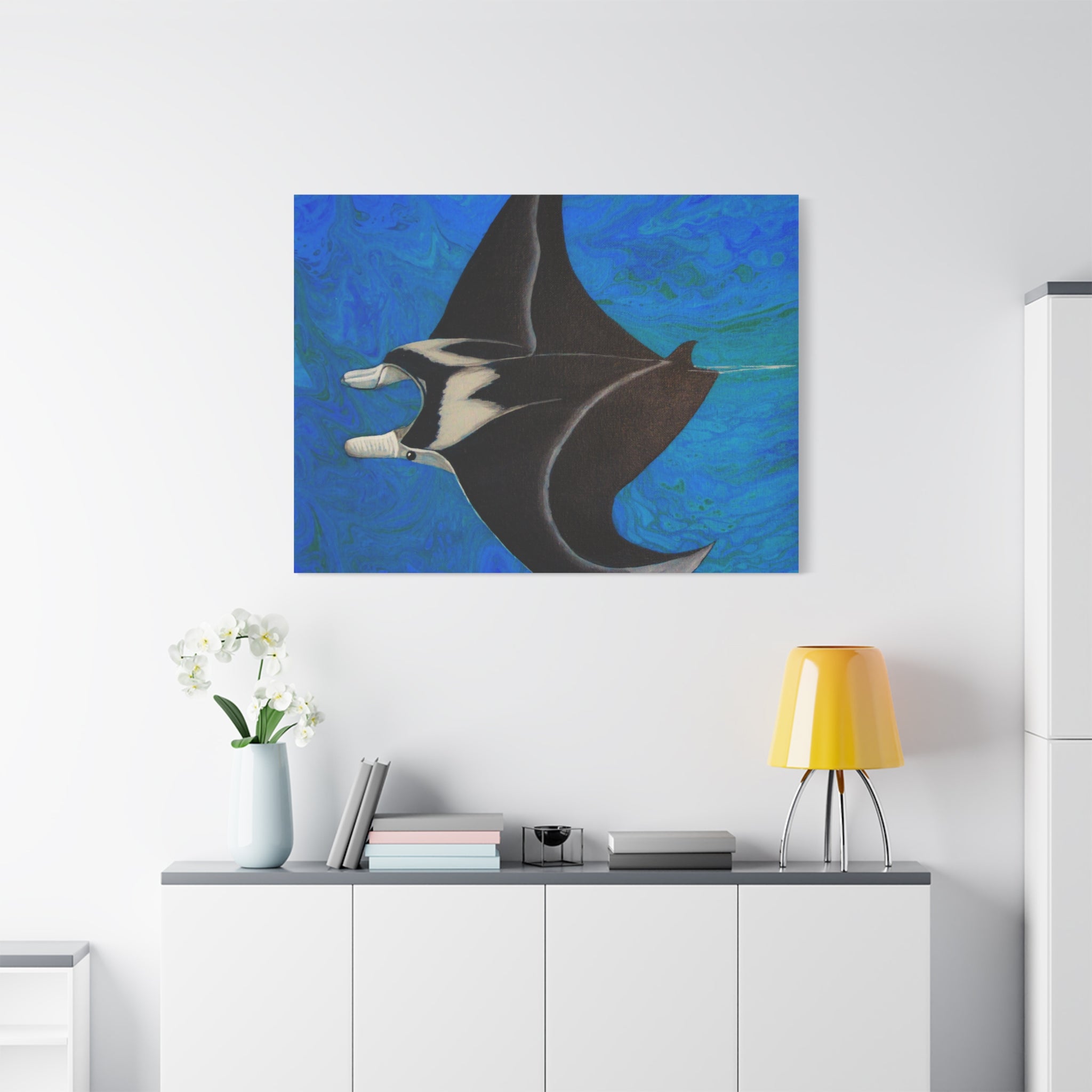 Canvas print of a manta ray on a blue abstract background above a white cabinet.