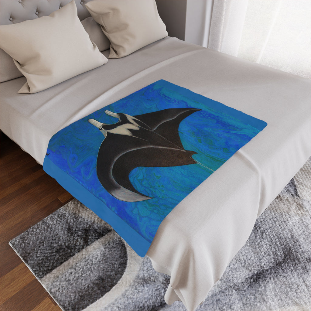 Bed with a decorative blanket featuring a manta ray design on a blue background.