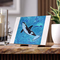 Orca whale painting on a stand with candles and a plant in the background tile