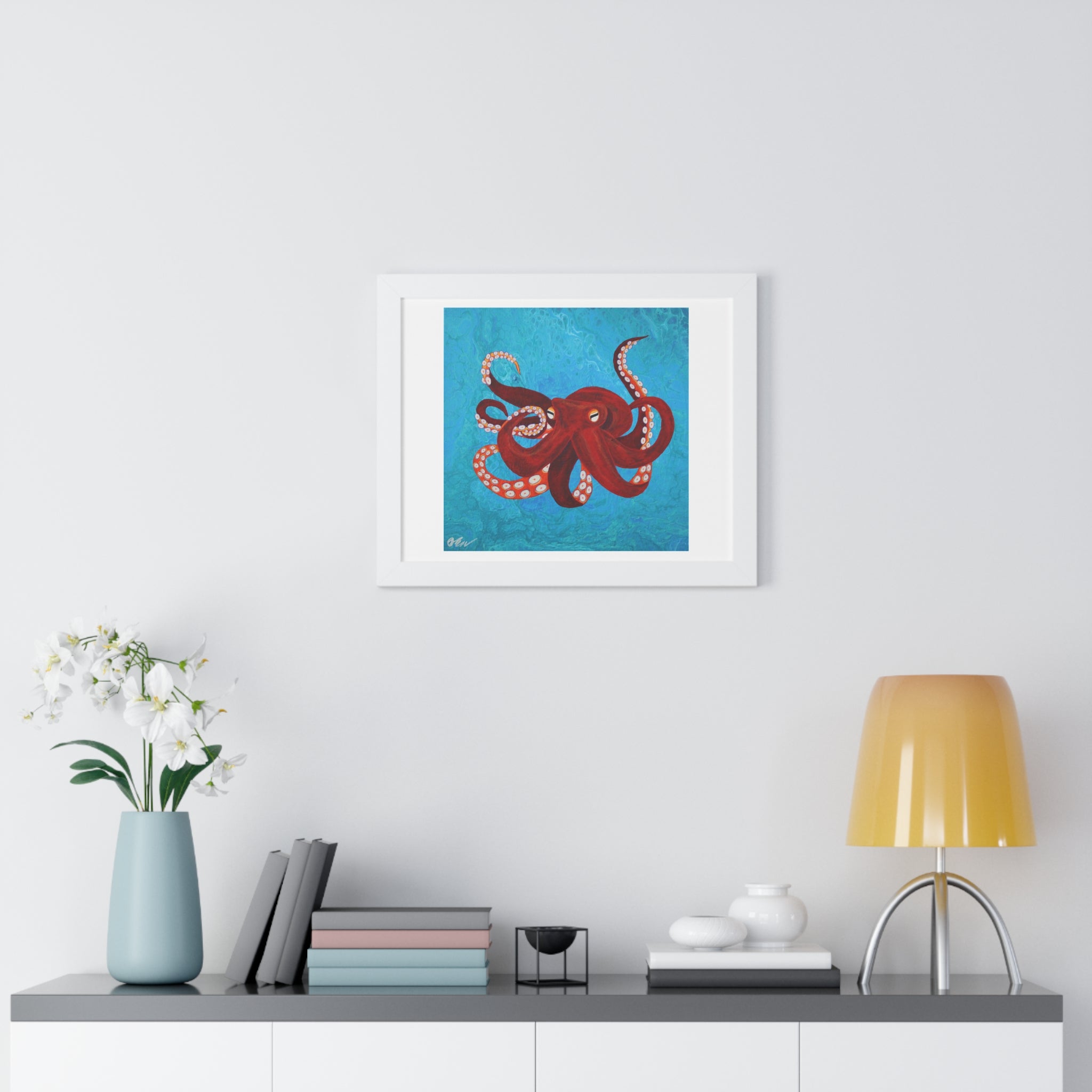 Framed artwork of a red octopus on a blue background, displayed above a desk with decor items.