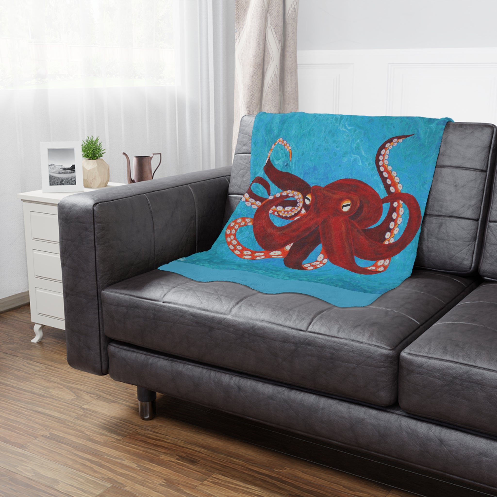 Blue blanket with red octopus design on a gray sofa in a living room.