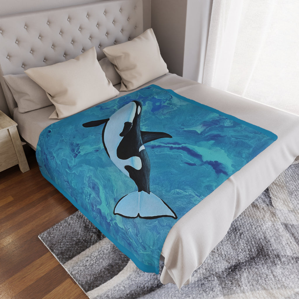 Bed with a decorative blanket featuring an orca whale design in a bedroom setting.