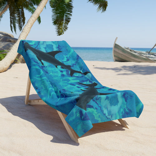 Beach towel/blanket with hammerhead shark design on a lounge chair at a beach.
