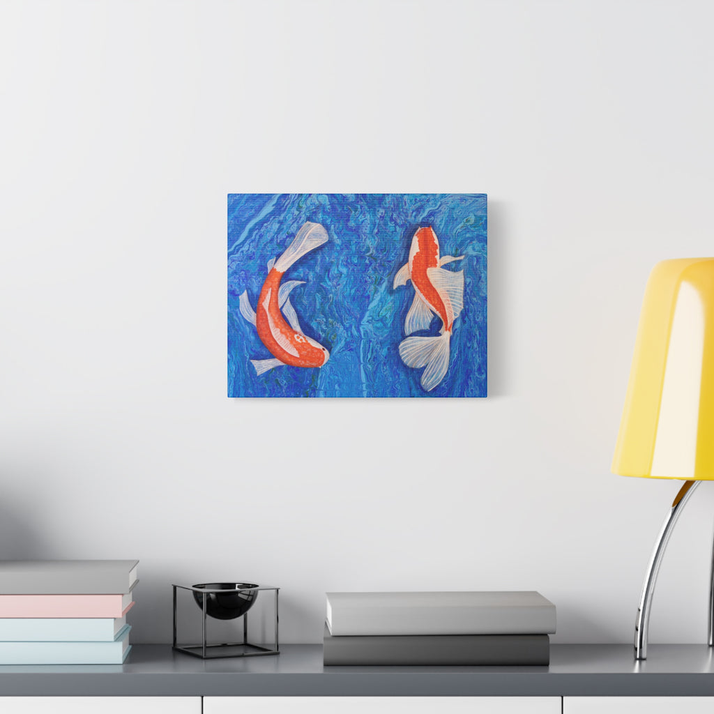 Canvas print of two koi fish on a blue background hanging on a wall above a desk.