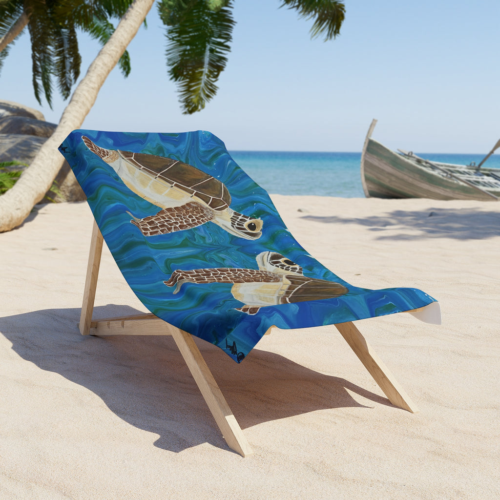 Beach towel/blanket with turtle design on a wooden chair at a sandy beach.