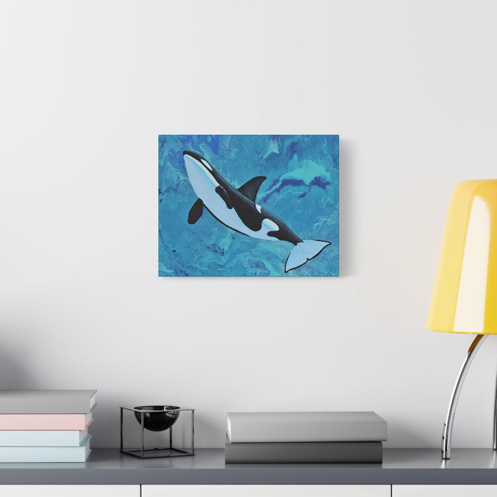 Canvas print of a whale painting on a wall above a desk with books and a lamp.