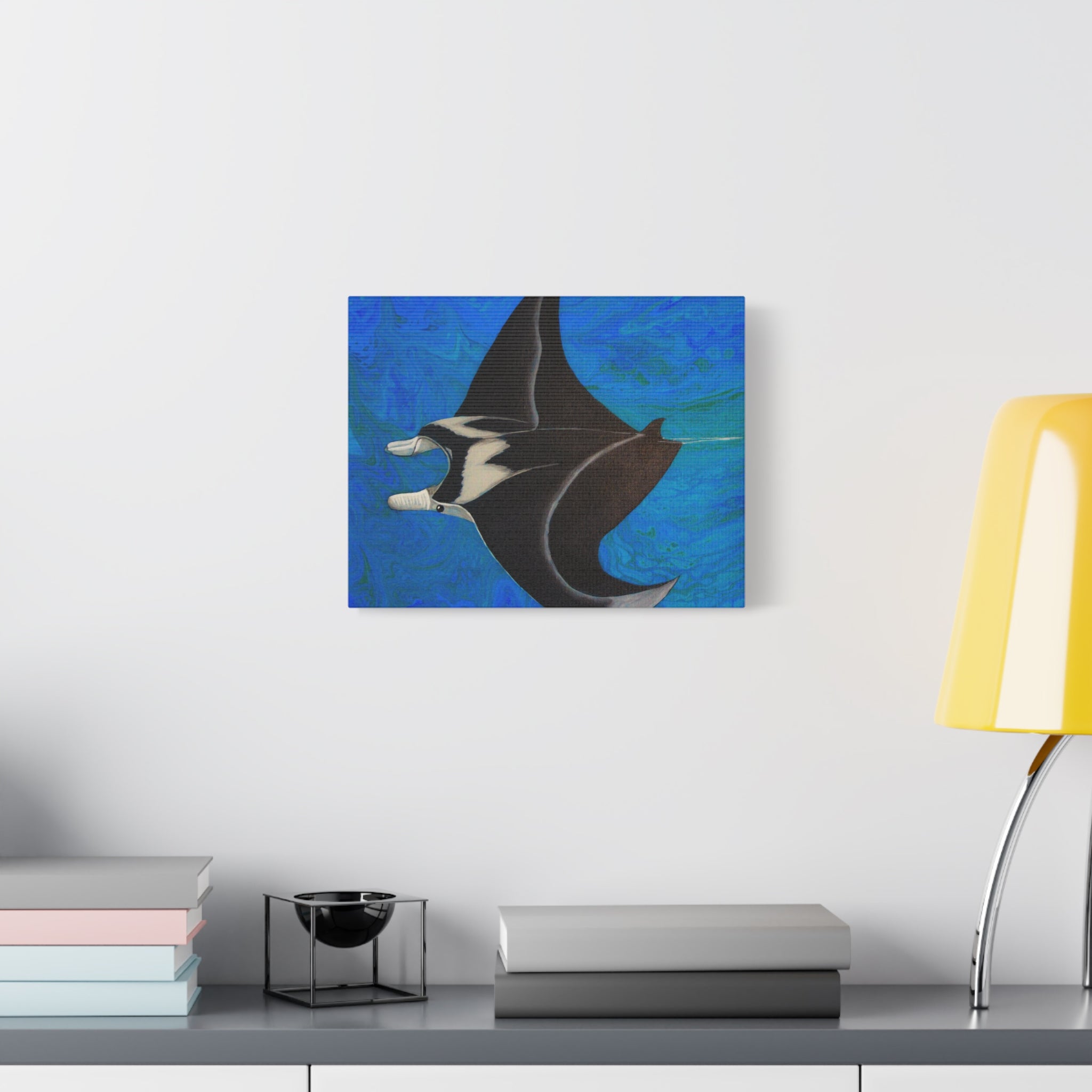 Abstract painting of a manta ray on a blue background, displayed on a wall above a desk.