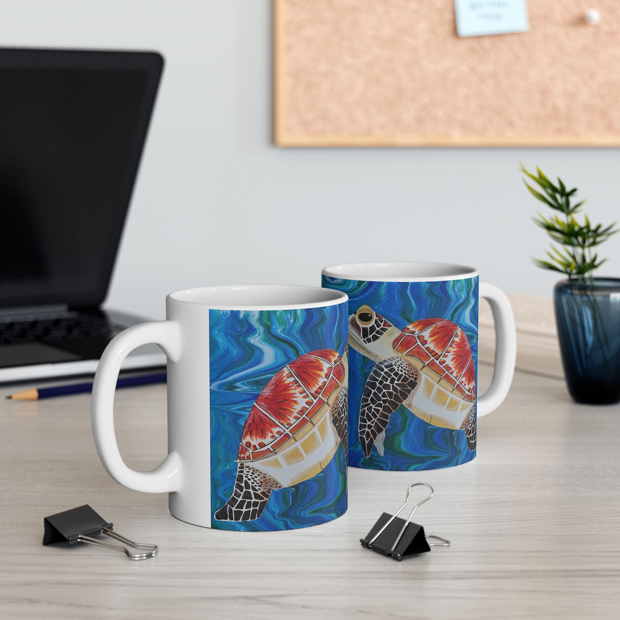 Two mugs with turtle designs on a desk with office supplies.
