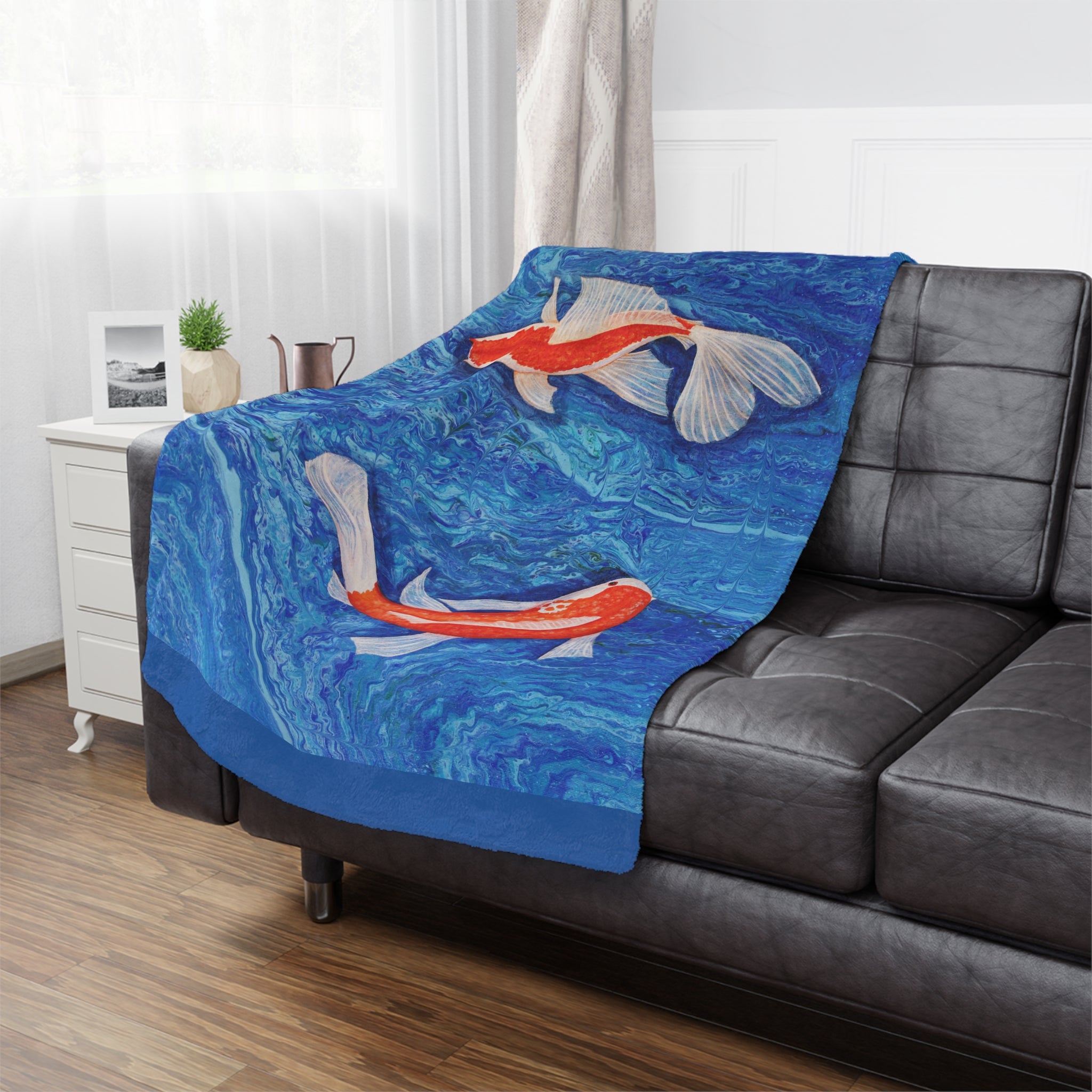 Blue blanket with fish design draped over a gray sofa in a living room.