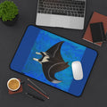 Desk setup with a blue desk pad featuring a manta ray design, a laptop, and office supplies.