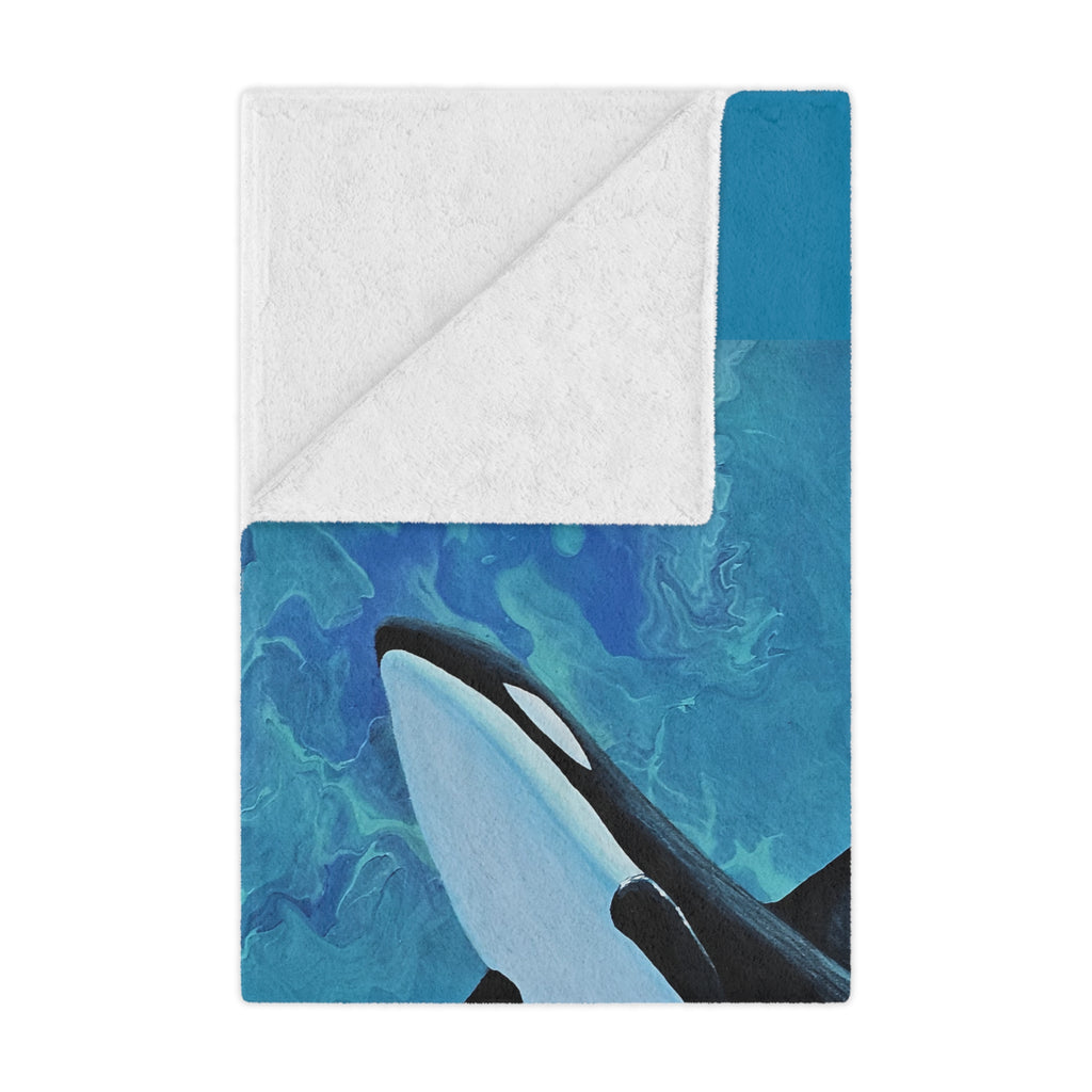 Blanket with an orca whale design on a blue and white background folded