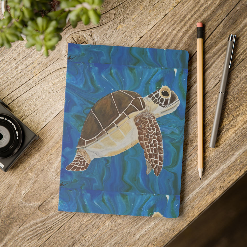 Notebook with a turtle illustration on a wooden surface with stationery items.