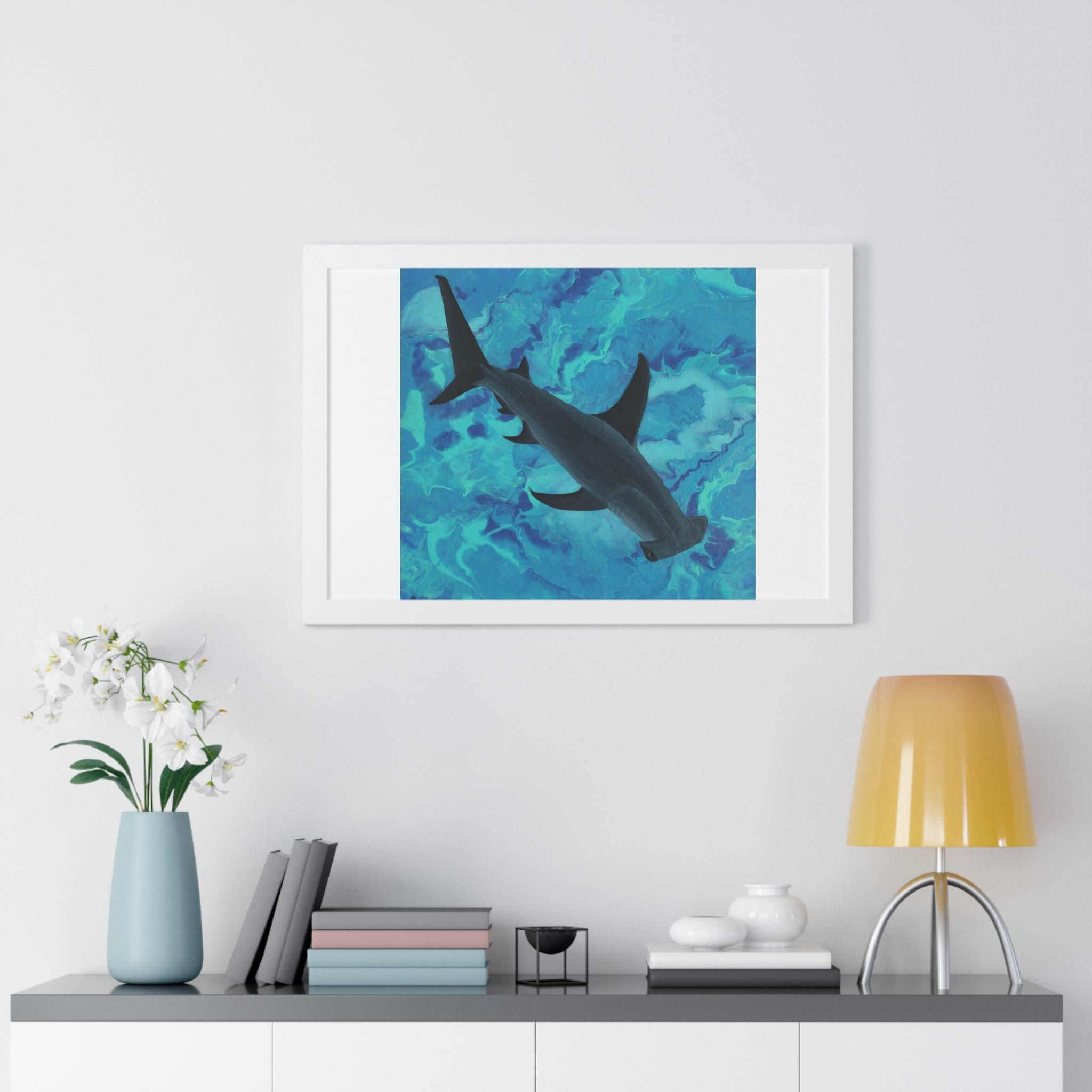 Framed artwork of a shark on a wall above a shelf with decor items.