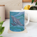 Mug with dolphin design on a coaster, placed on a surface with a plant and container in the background.