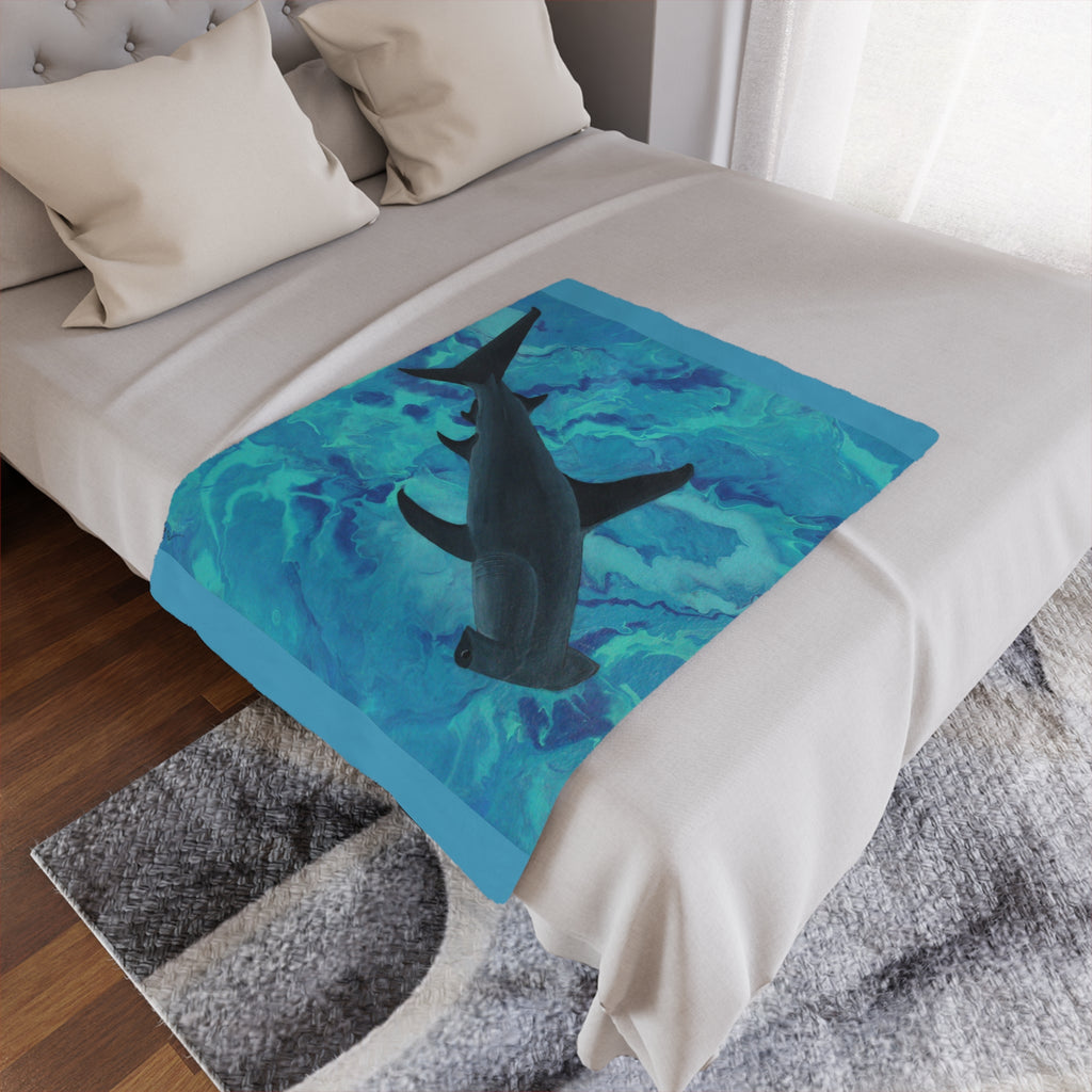 Bed with a shark-themed blanket featuring a blue and green abstract design.