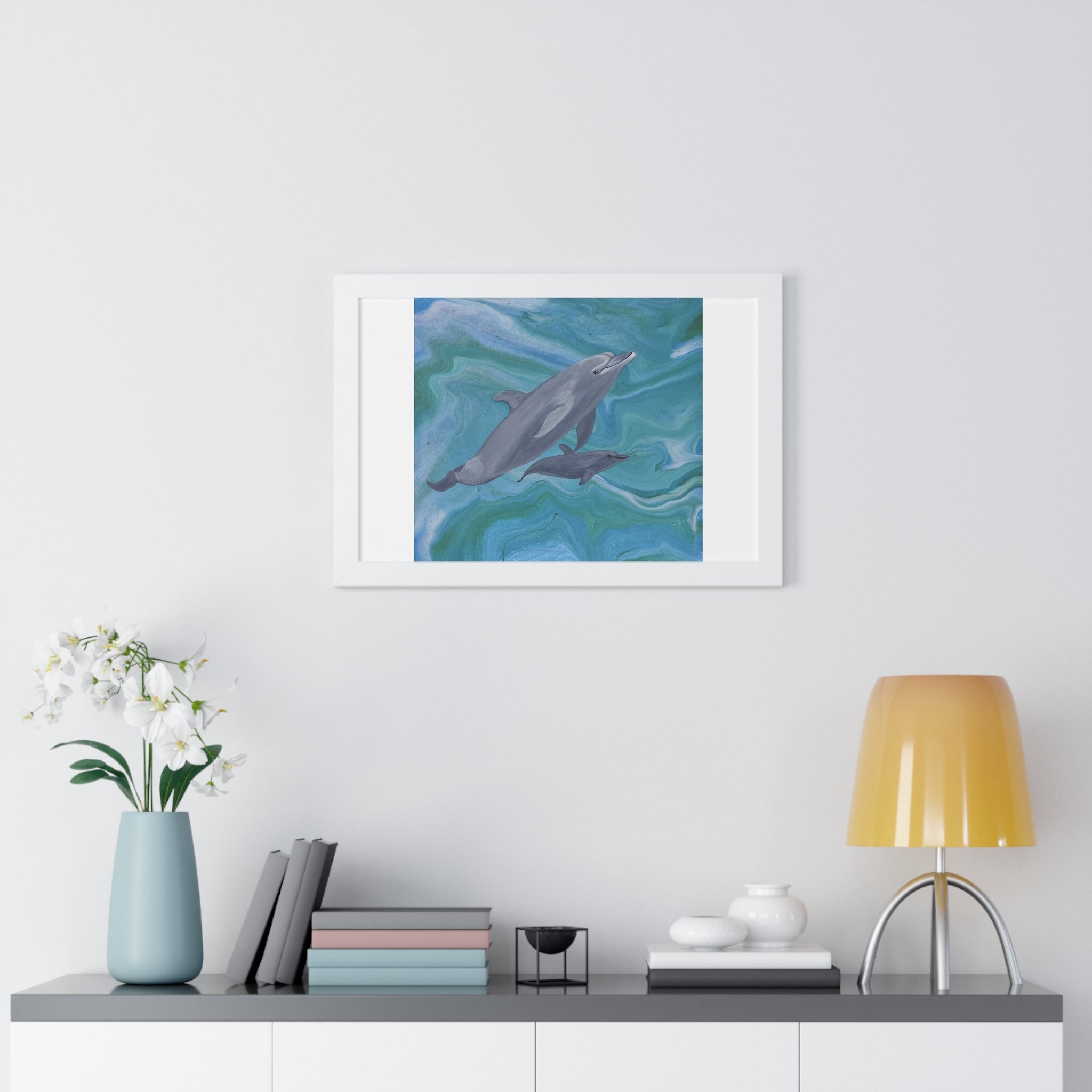 Framed artwork of dolphins on a wall above a shelf with decor items.