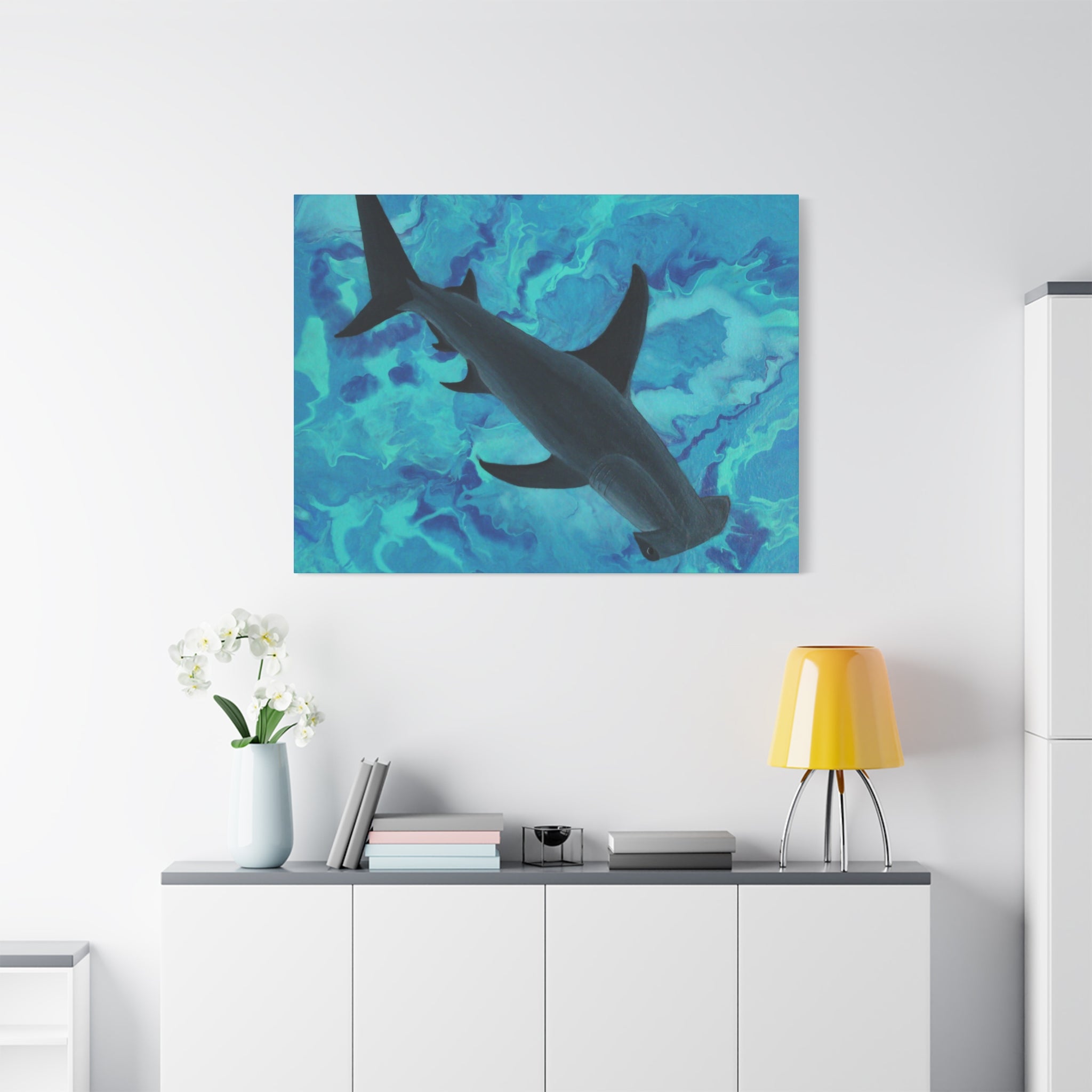 Shark painting on a wall above a white cabinet with decor items.