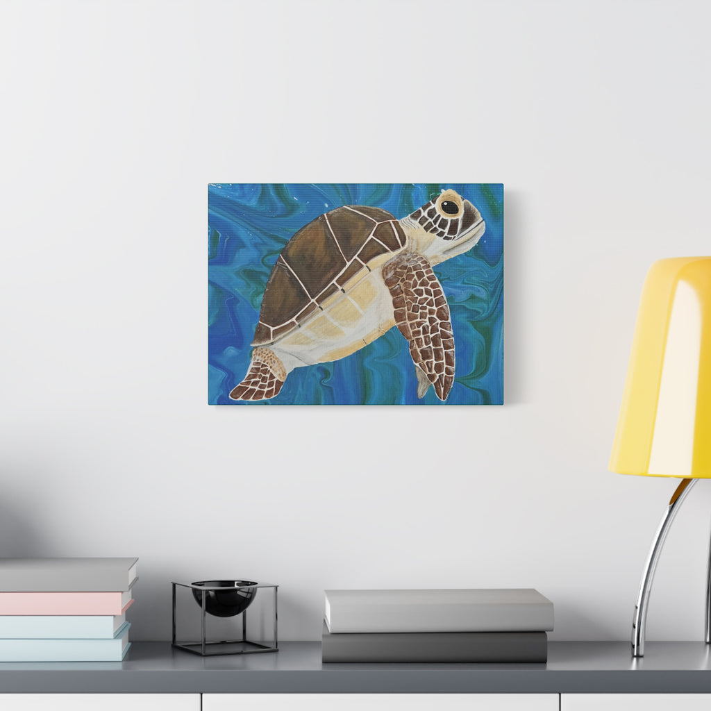 Canvas print of a turtle on a blue background hanging above a desk with books and a lamp.