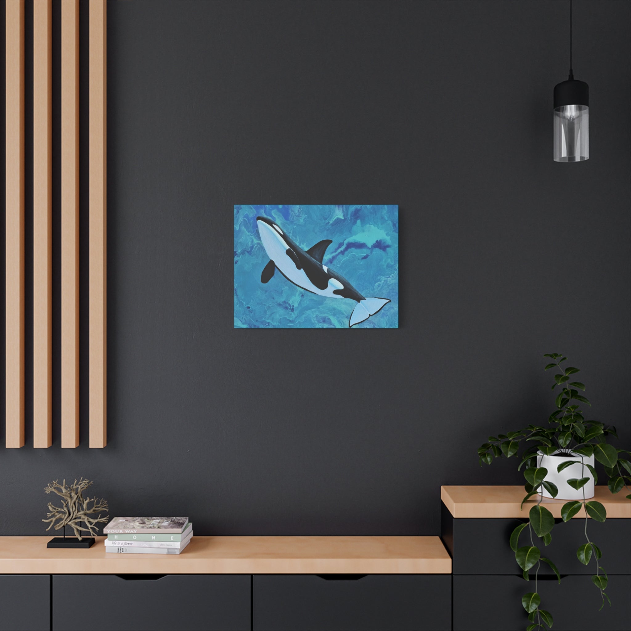 Orca whale painting on a dark wall above a wooden shelf with books and decor.