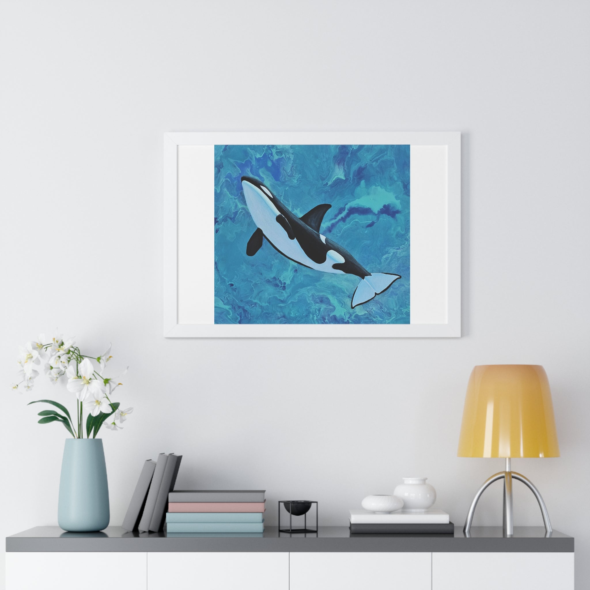Framed artwork of a whale on a wall above a shelf with decor items.