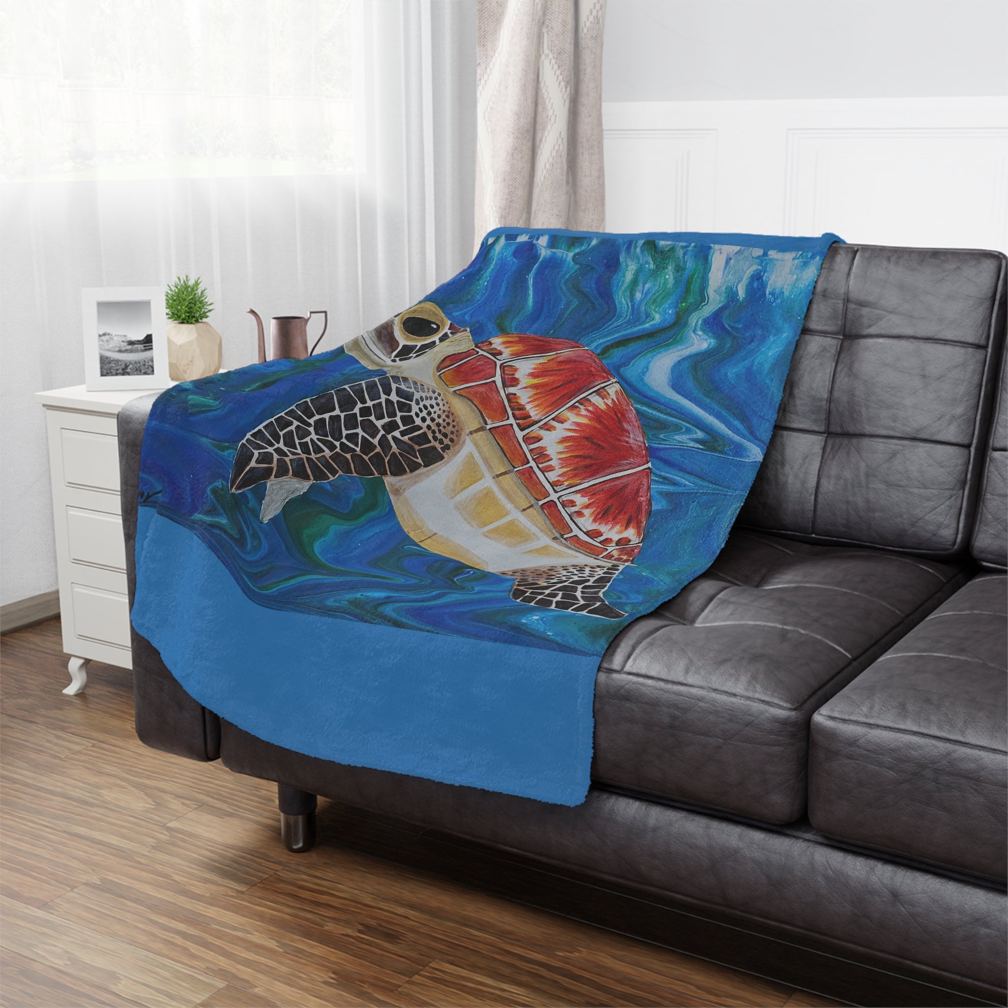 Colorful turtle blanket draped over a gray sofa in a living room setting.