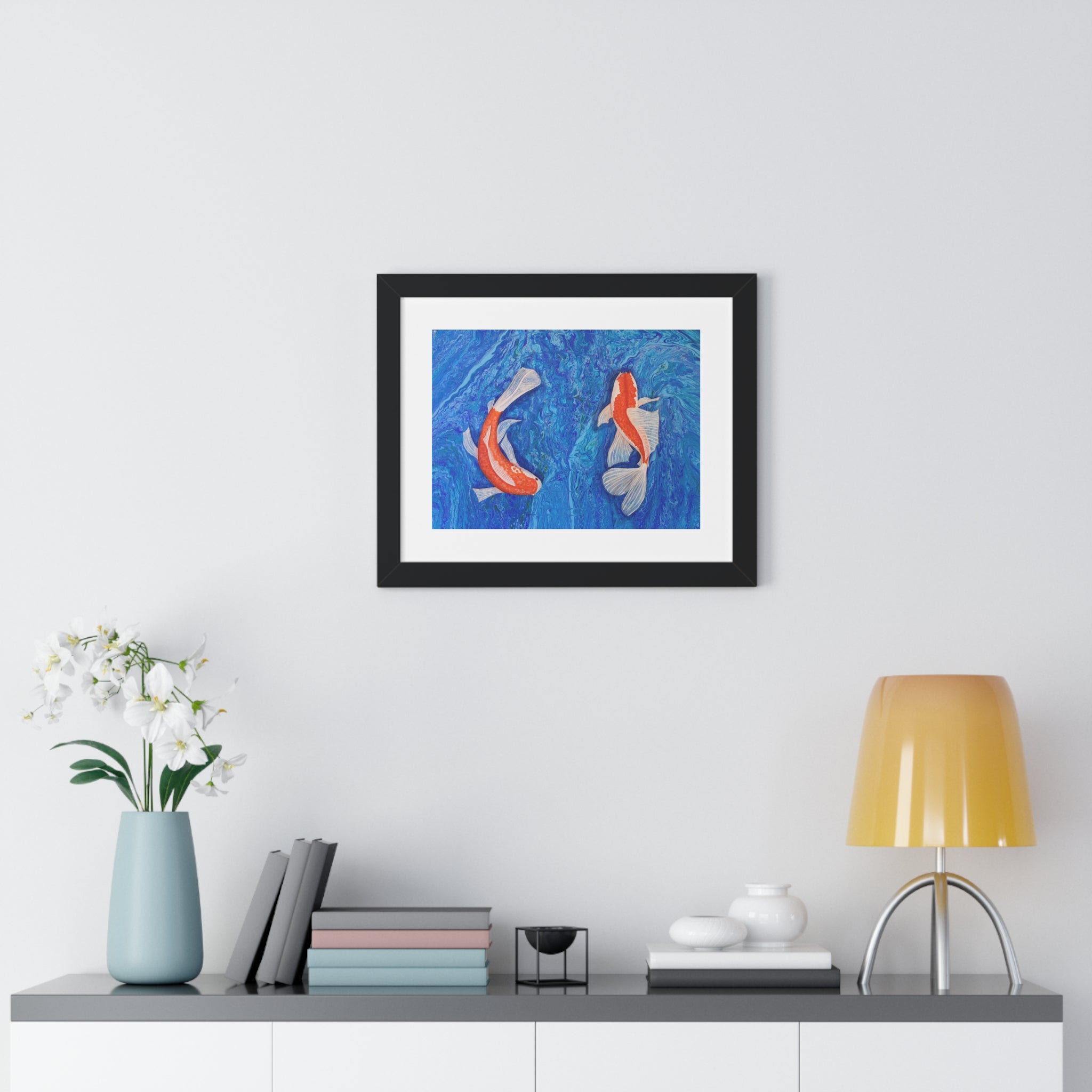 Framed artwork of koi fish on a wall above a shelf with decor items.