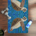 Yoga mat with turtle design on a wooden floor with weights and a water bottle.