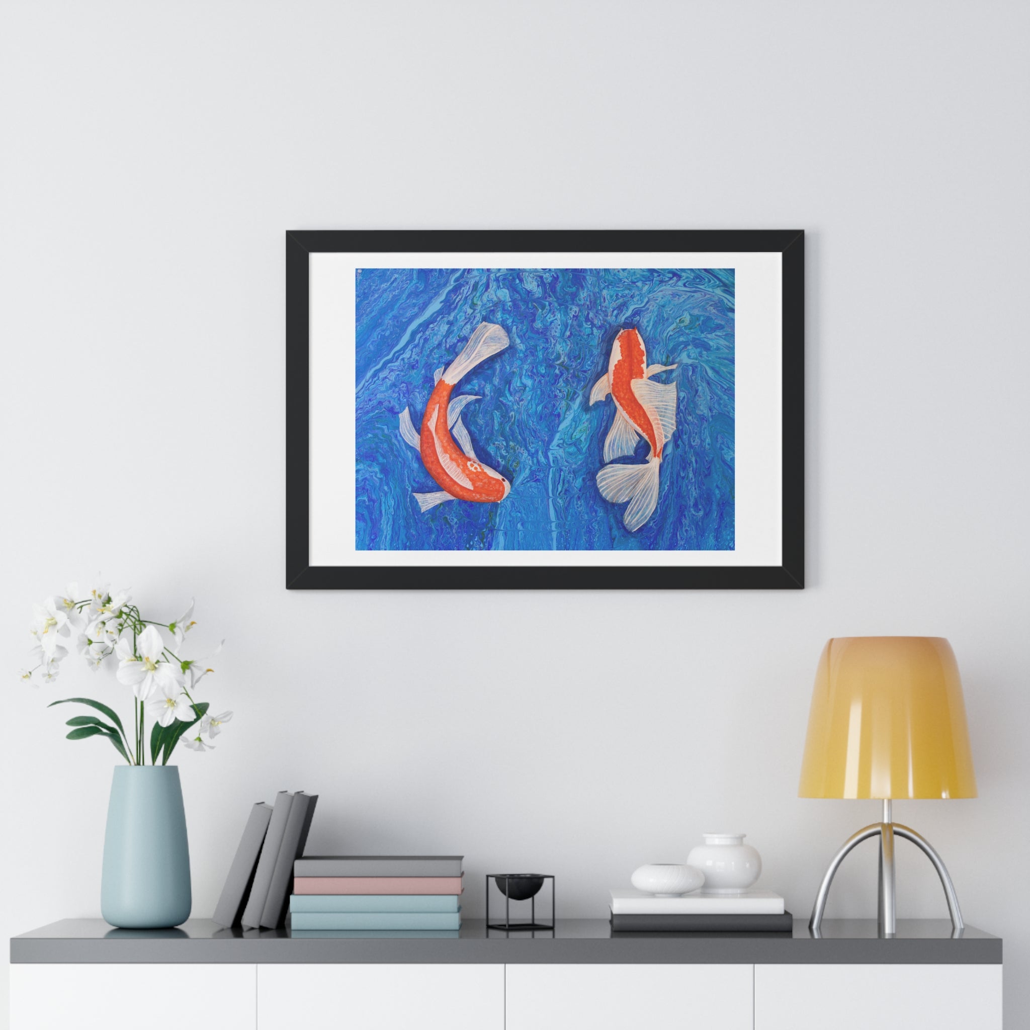 Framed artwork of two koi fish on a blue background, displayed on a wall above a shelf with decor items.