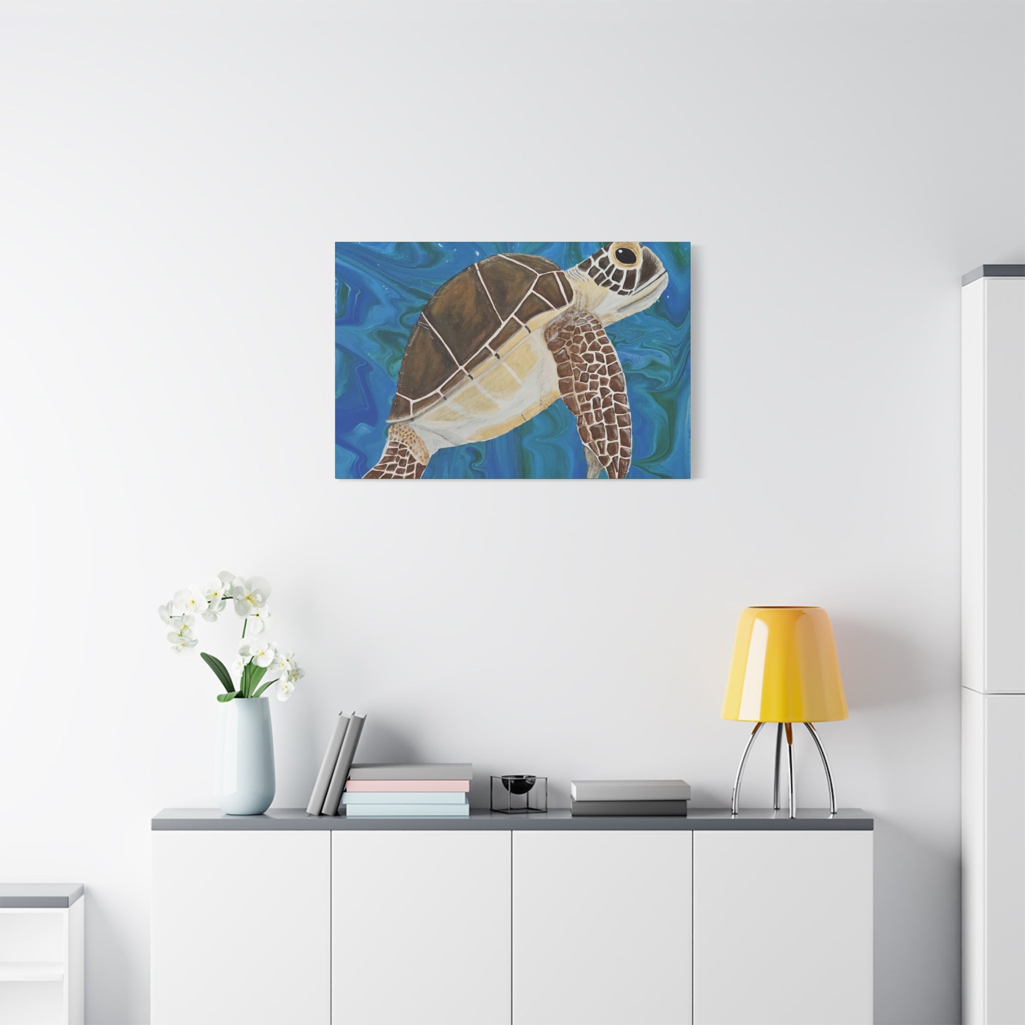Canvas print of a turtle on a wall above a white cabinet with a yellow lamp.