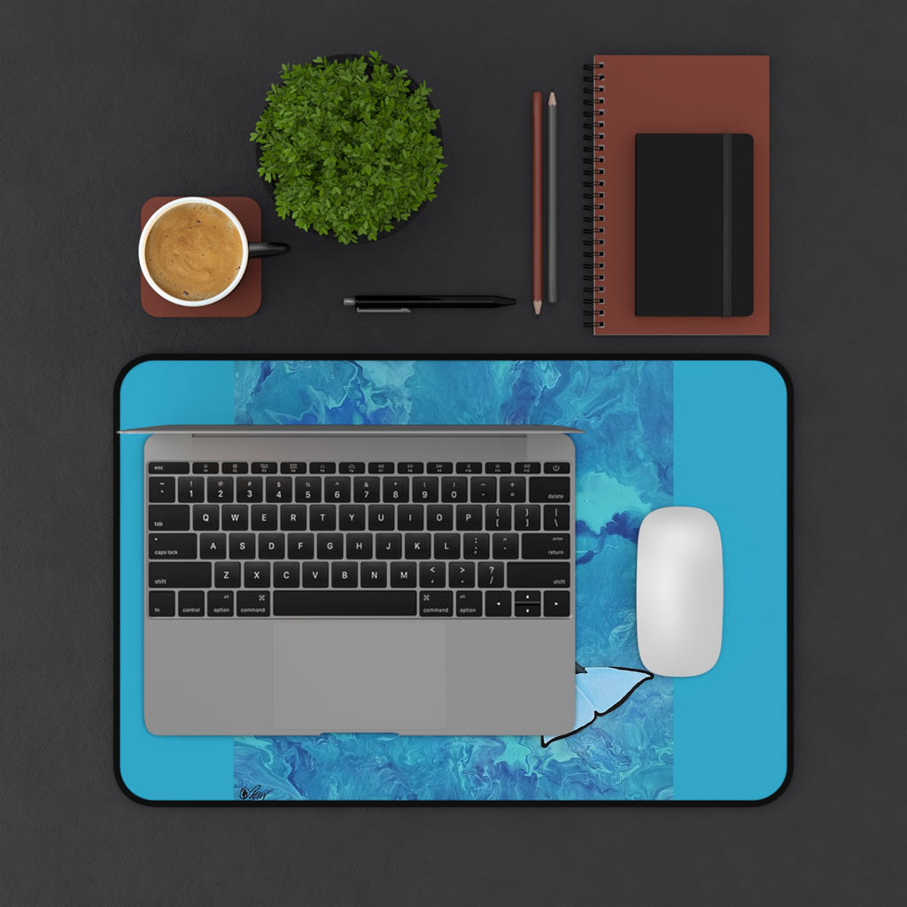 Laptop on a blue desk pad with a coffee cup, plant, and stationery items on a dark surface
