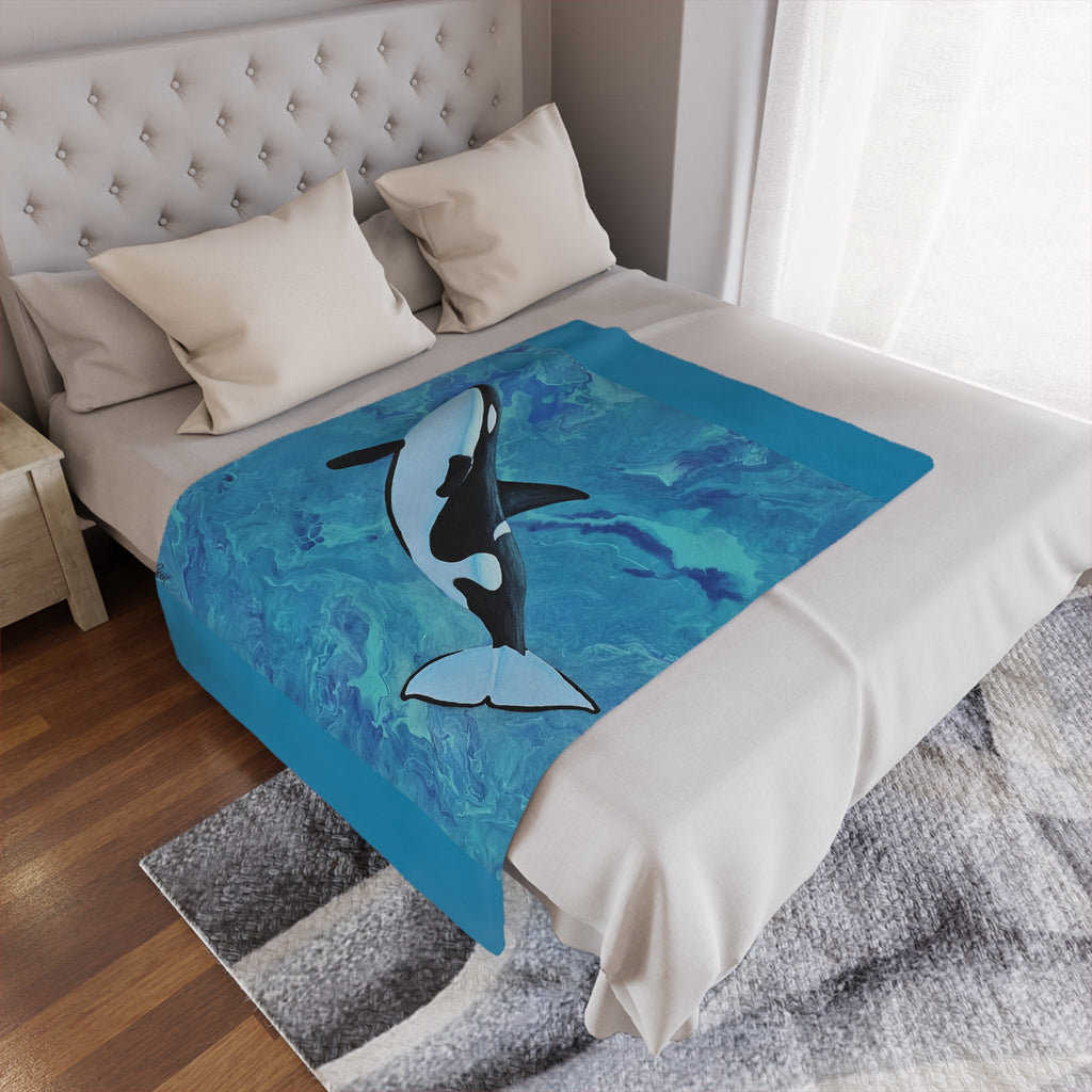 Bed with a blue blanket featuring an orca whale design, in a bedroom setting.
