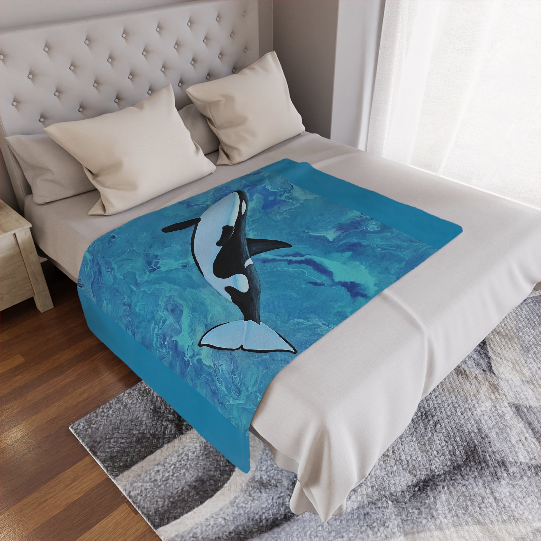 Bed with a blue blanket featuring an orca whale design, in a bedroom setting.