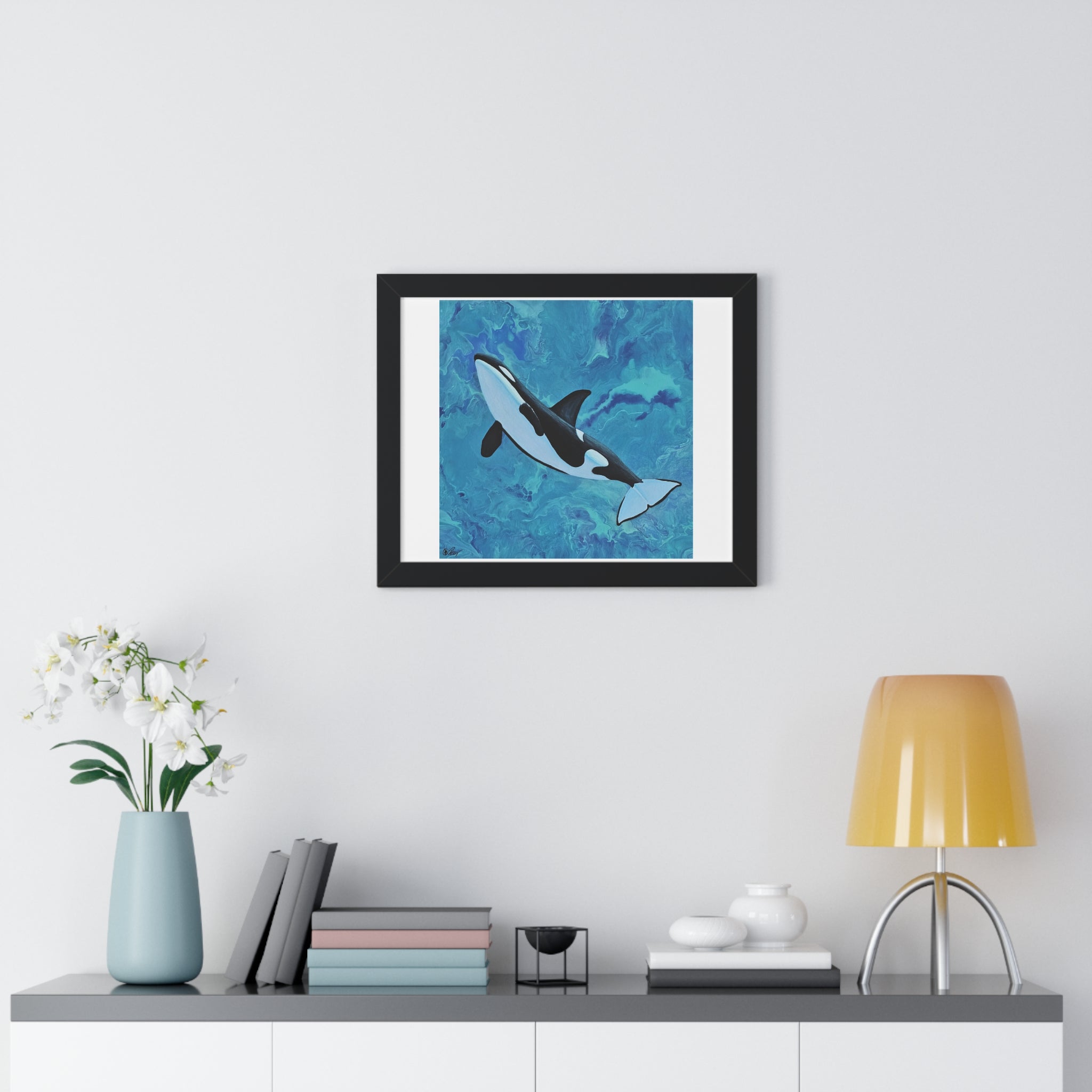 Framed artwork of a whale on a wall above a shelf with decor items.