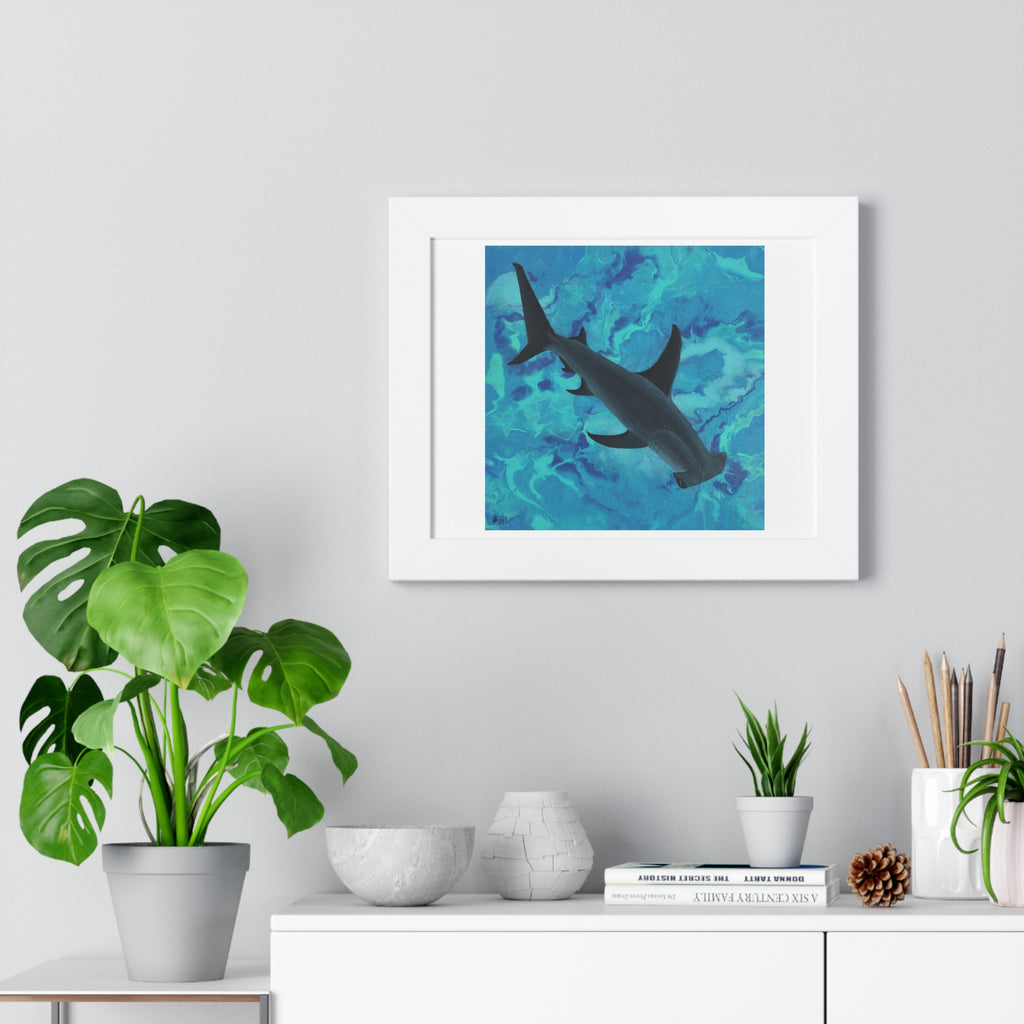 Framed artwork of a shark in water on a wall above a desk with plants and decor.