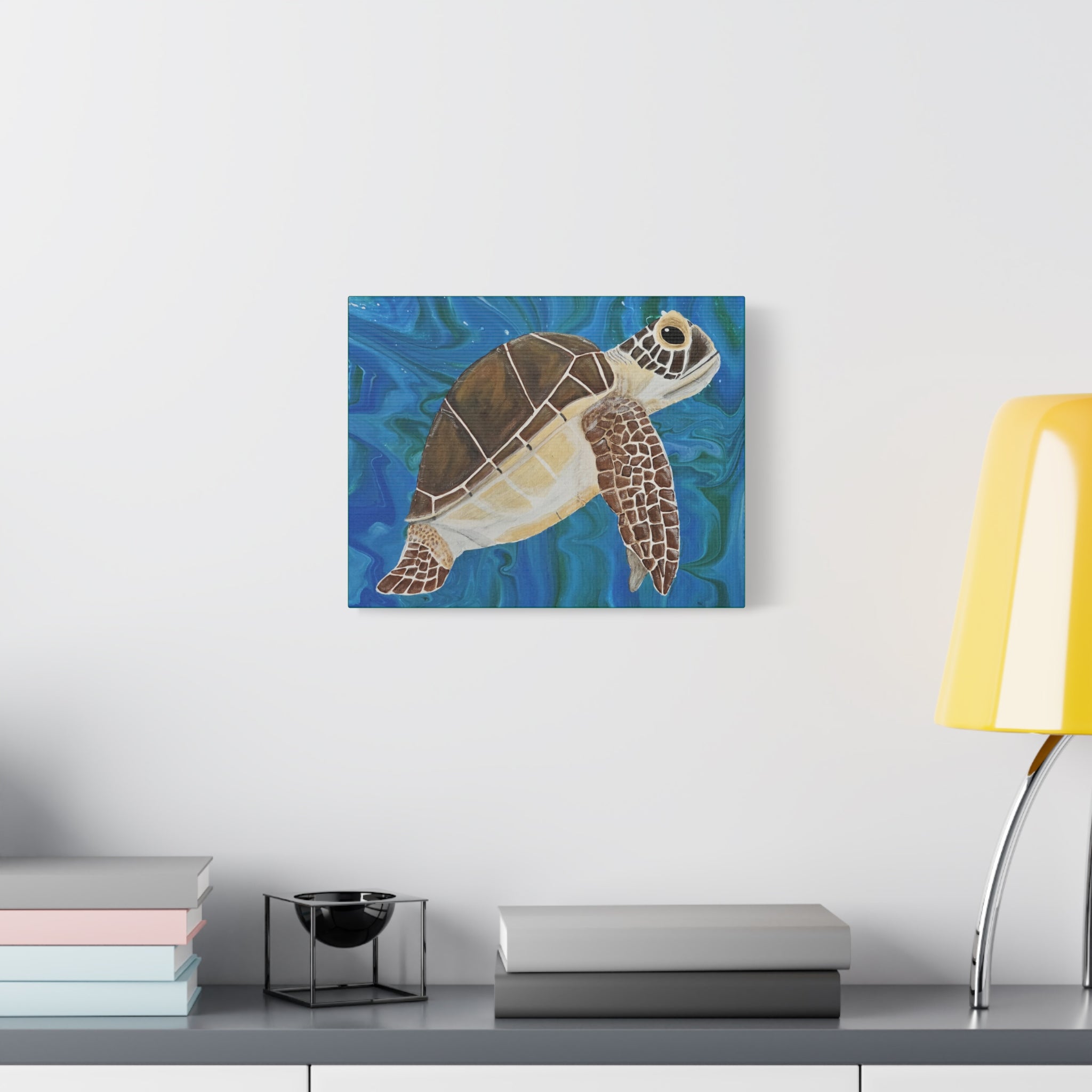 Canvas print of a turtle on a blue wave background, displayed on a wall above a desk.