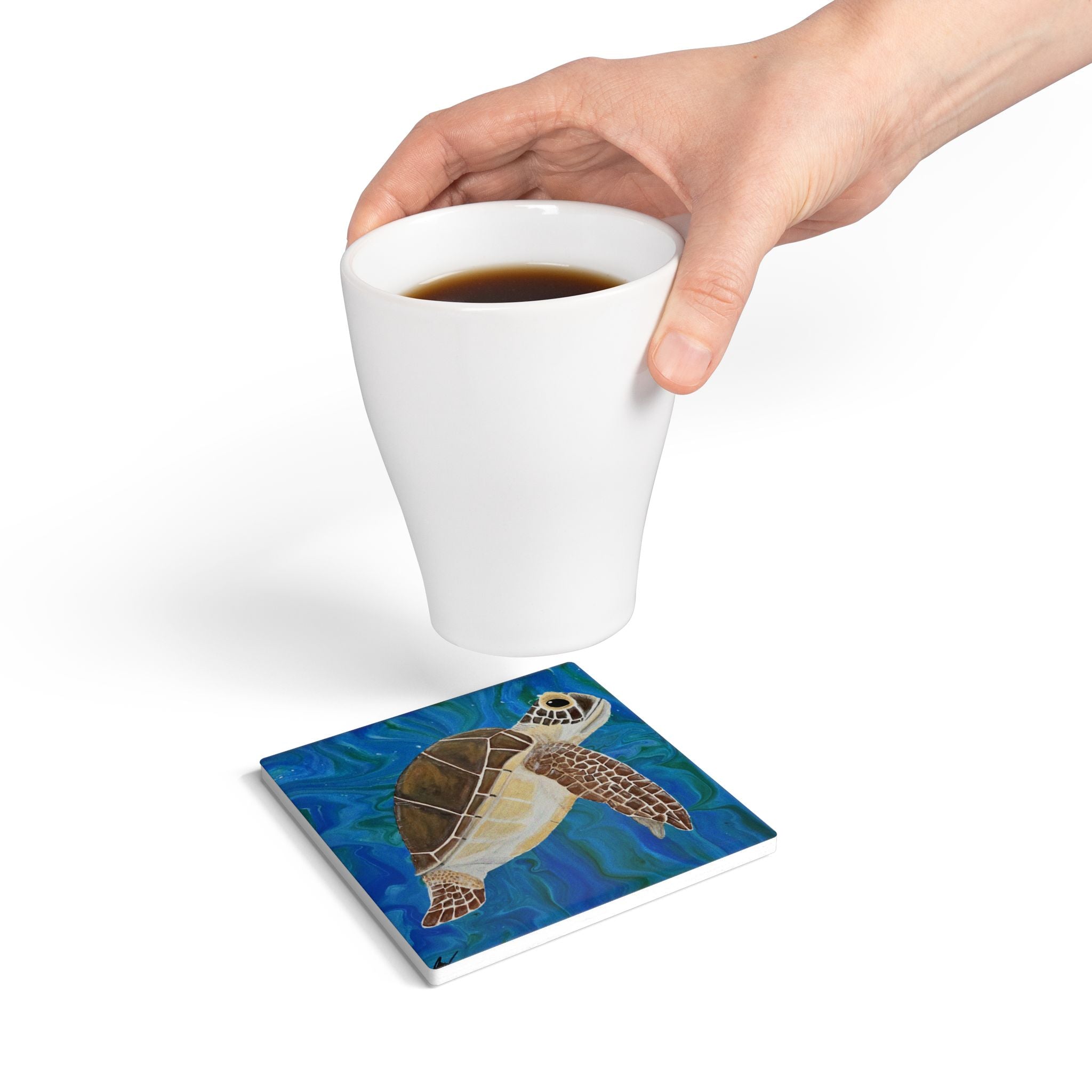 Coaster with turtle design under a white cup of coffee