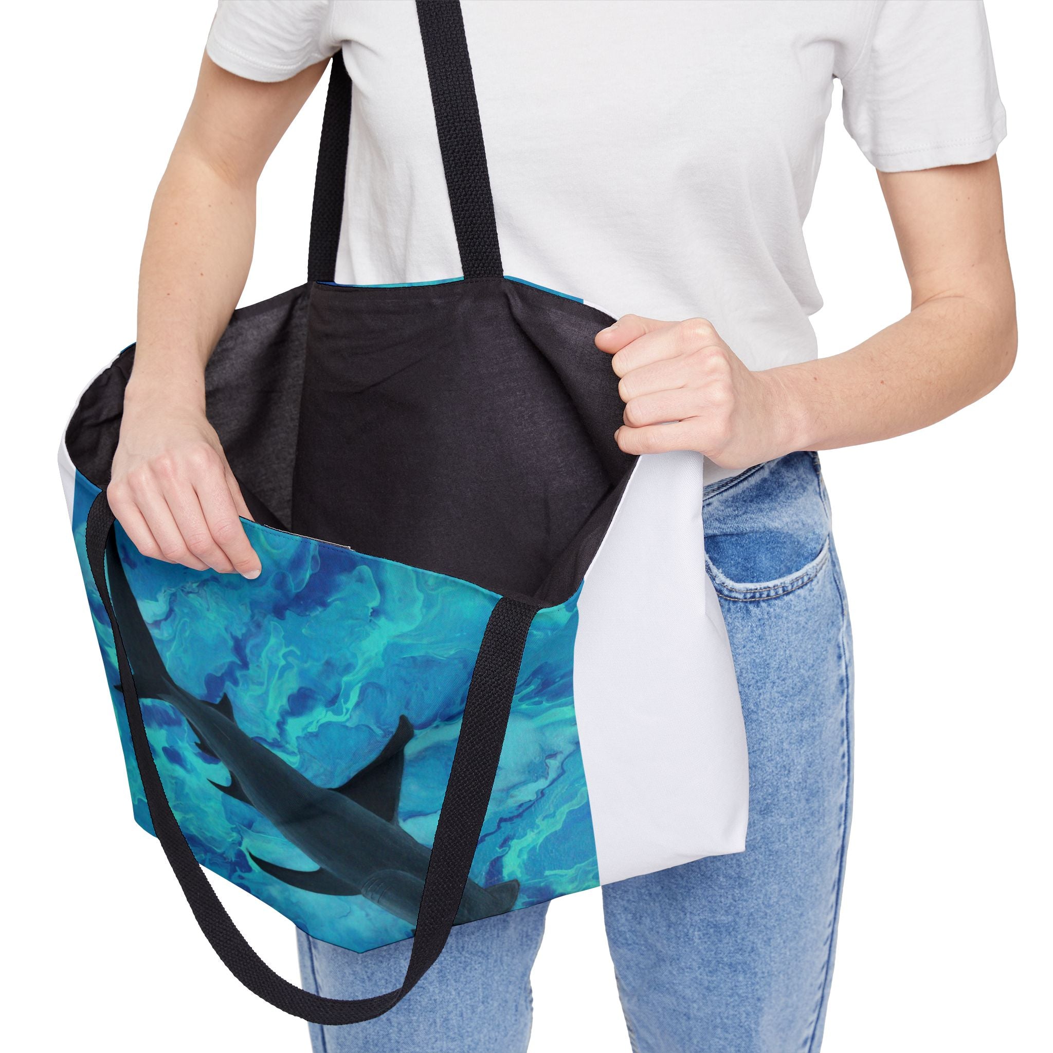 Person holding a blue camouflage with shark tote bag with black straps on a white background