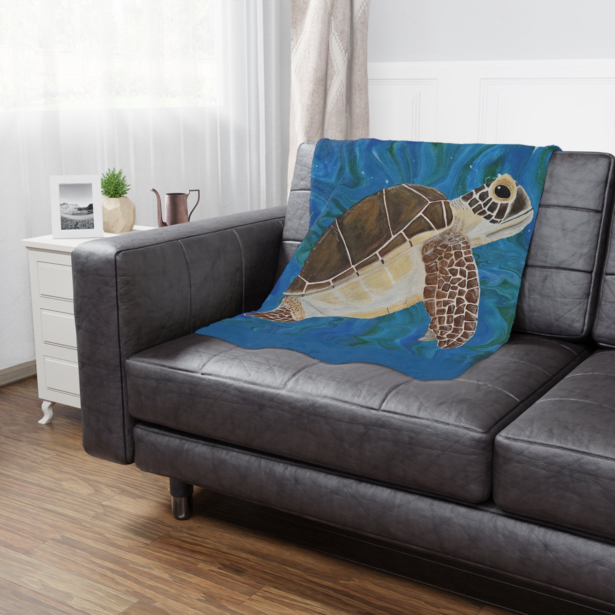 Gray sofa with a turtle-themed blanket in a living room setting