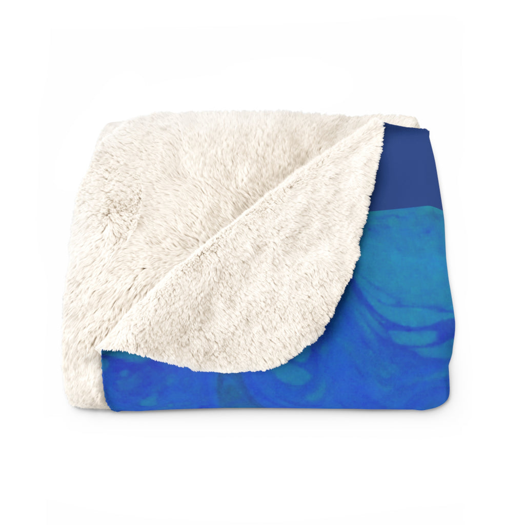 Folded blanket with white sherpa interior and blue abstract pattern exterior on a white background