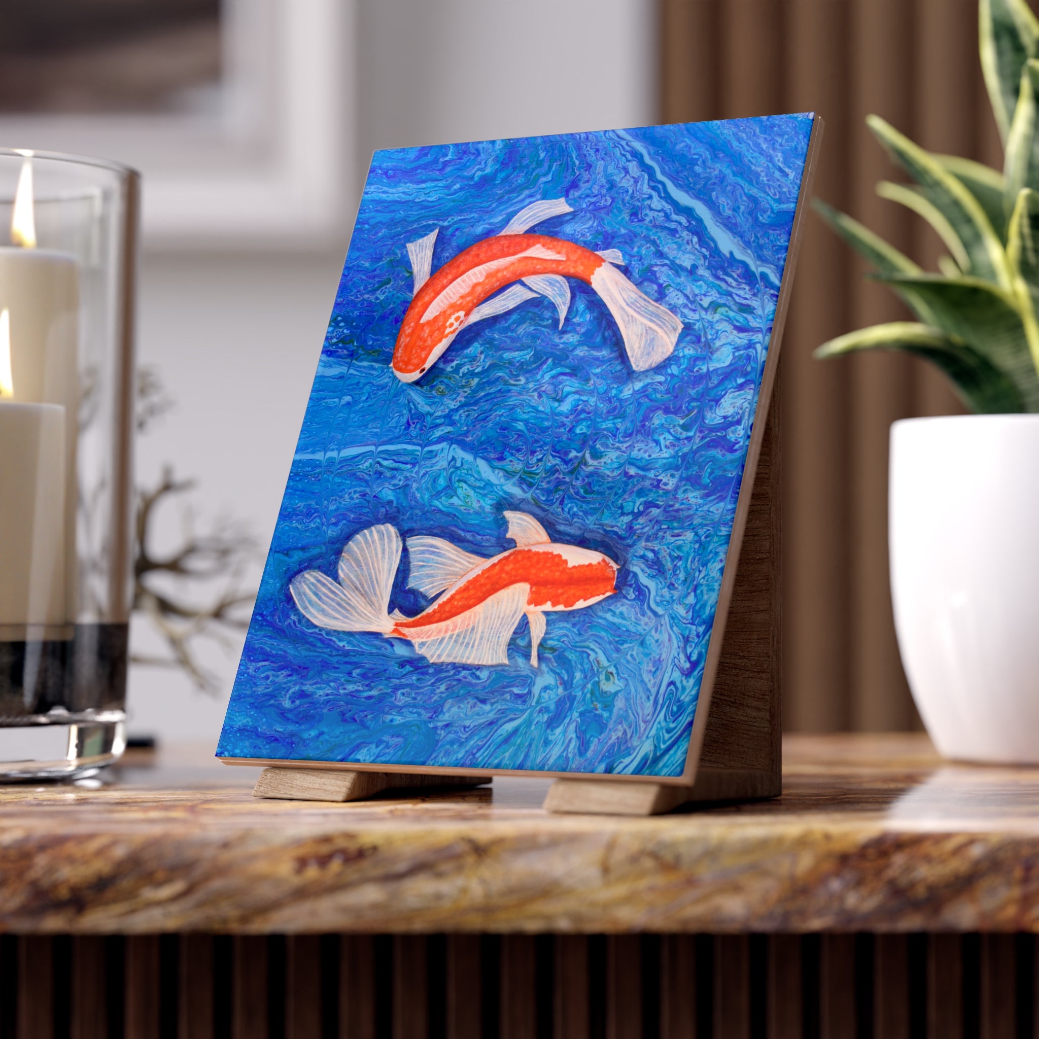 Artistic depiction of two koi fish on a blue background tile, displayed on a wooden stand.