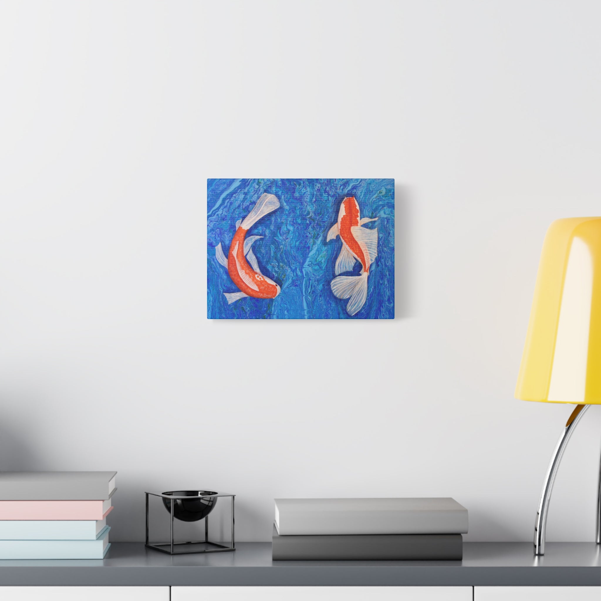Canvas print of two koi fish on a blue background hanging on a wall above a desk.